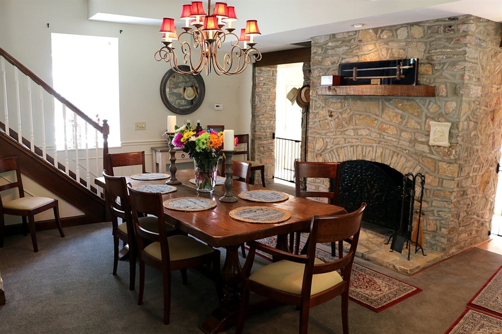 The centerpiece to the living room is a massive stone fireplace with a wood-beam mantel. The fireplace is flanked by two separate walkways into the kitchen and mudroom area of the house. An open staircase leads from the dining room and wraps up to a loft balcony above the living room. CONTRIBUTED PHOTO BY KATHY TYLER