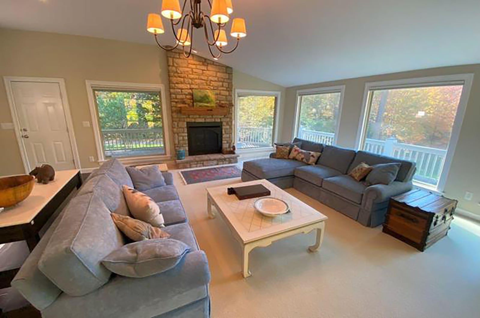 The great room has a vaulted ceiling, neutral carpeting and a floor to ceiling stone gas fireplace.