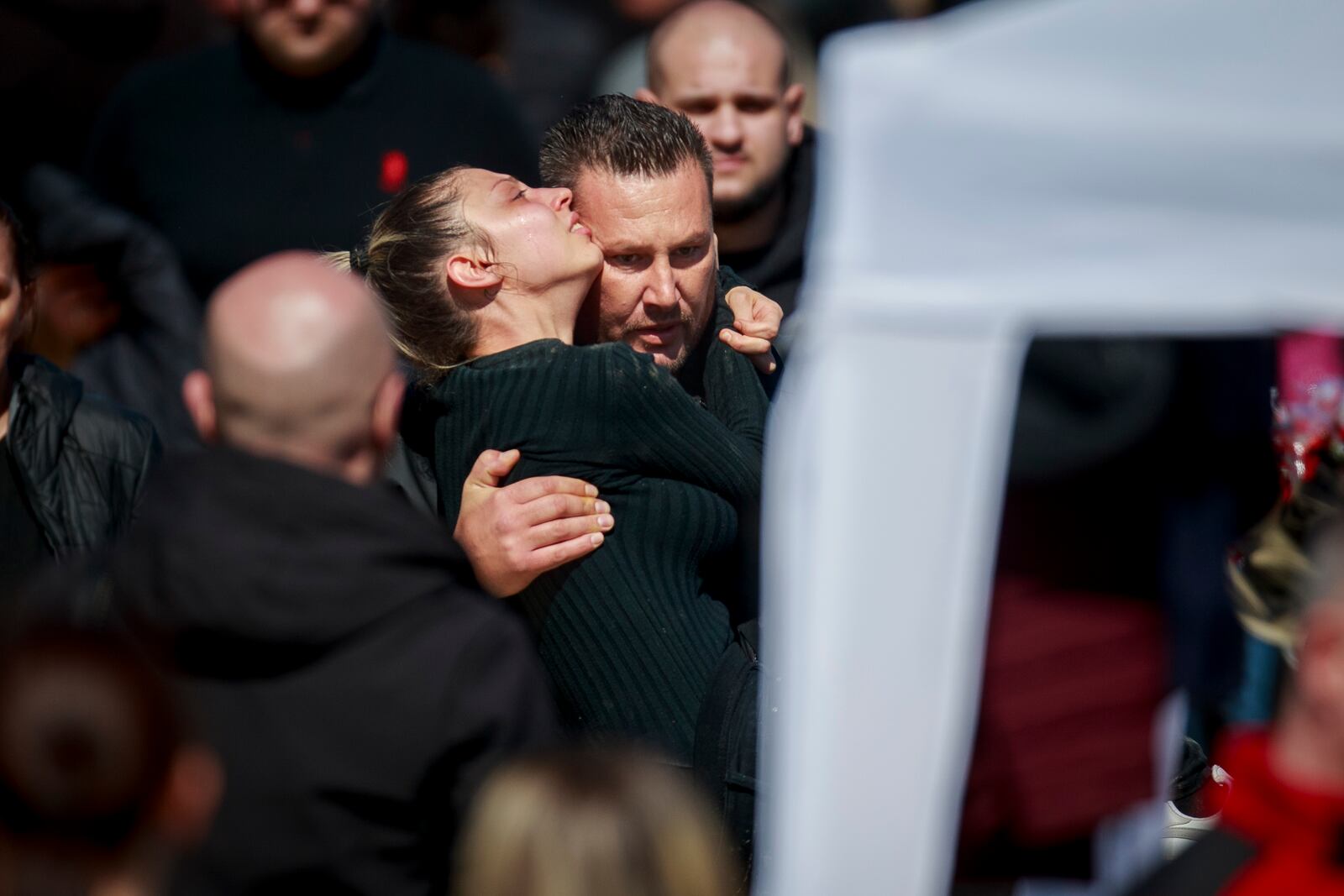 A man carries a woman who collapsed to the paramedics tent during the funeral ceremony of the victims of a massive nightclub fire in the town of Kocani, North Macedonia, Thursday, March 20, 2025. (AP Photo/Visar Kryeziu)