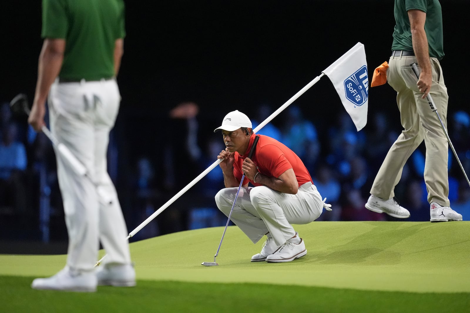 Tiger Woods helps Jupiter Links Golf Club teammate Tom Kim, not pictured, line up a putt during a match of the TMRW Golf League (TGL) against Boston Common Golf, Monday, Jan. 27, 2025, in Palm Beach Gardens, Fla. (AP Photo/Rebecca Blackwell)