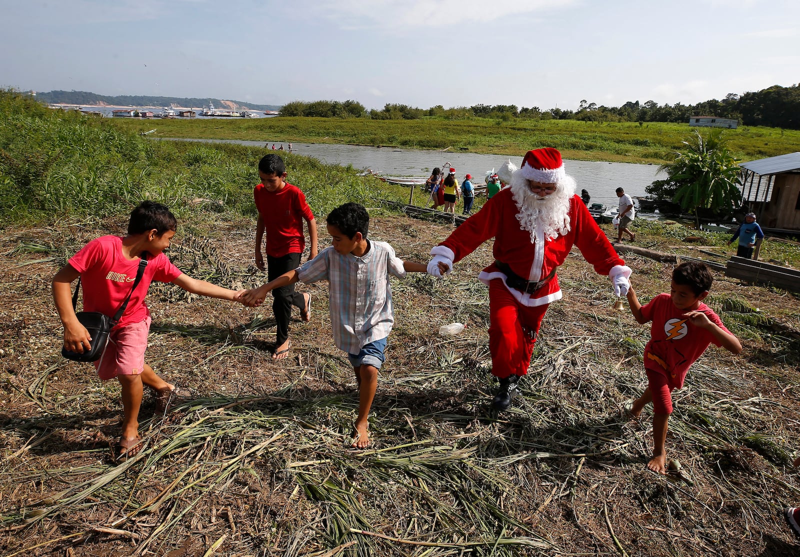 Jorge Barroso, dressed as Santa Claus, is received by young residents after arriving on a boat to distribute Christmas gifts to children who live in the riverside communities of the Amazon, in Iranduba, Brazil, Saturday, Dec. 21, 2024. (AP Photo/Edmar Barros)