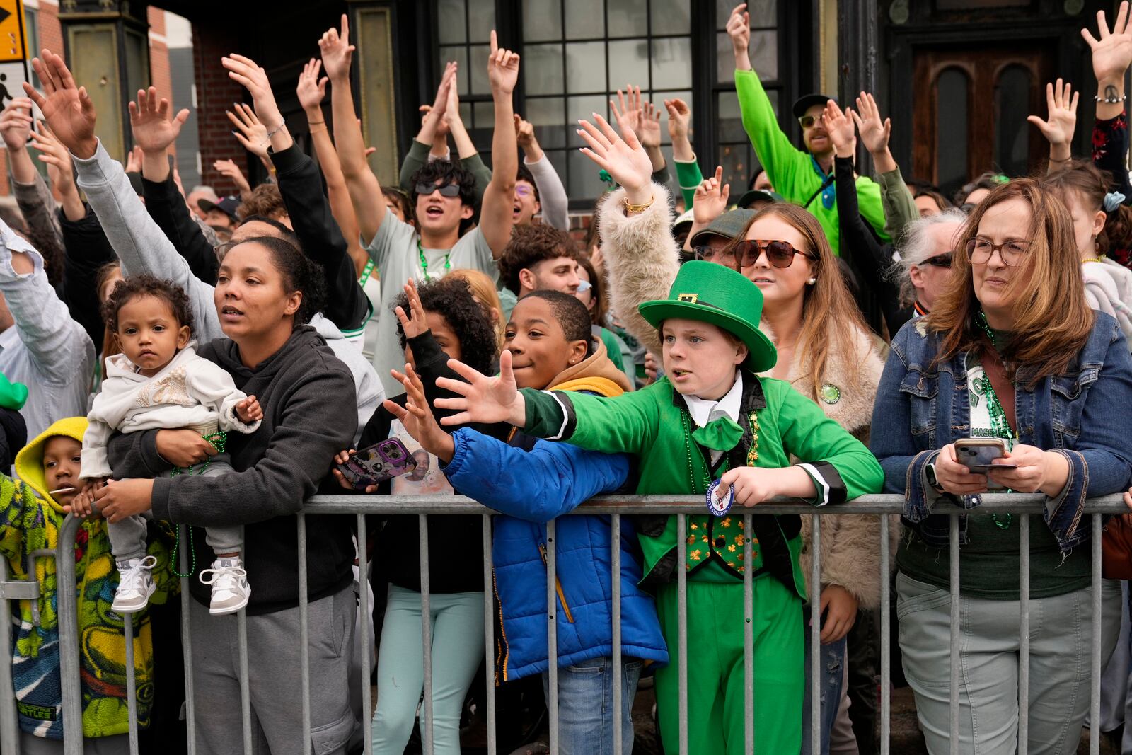 Graham Johnston, of St. Louis, Mo., dressed as a leprechaun, and others reach for treats thrown by participants at the St. Patrick's Day parade, Sunday, March 16, 2025, in Boston, Mass. (AP Photo/Robert F. Bukaty)