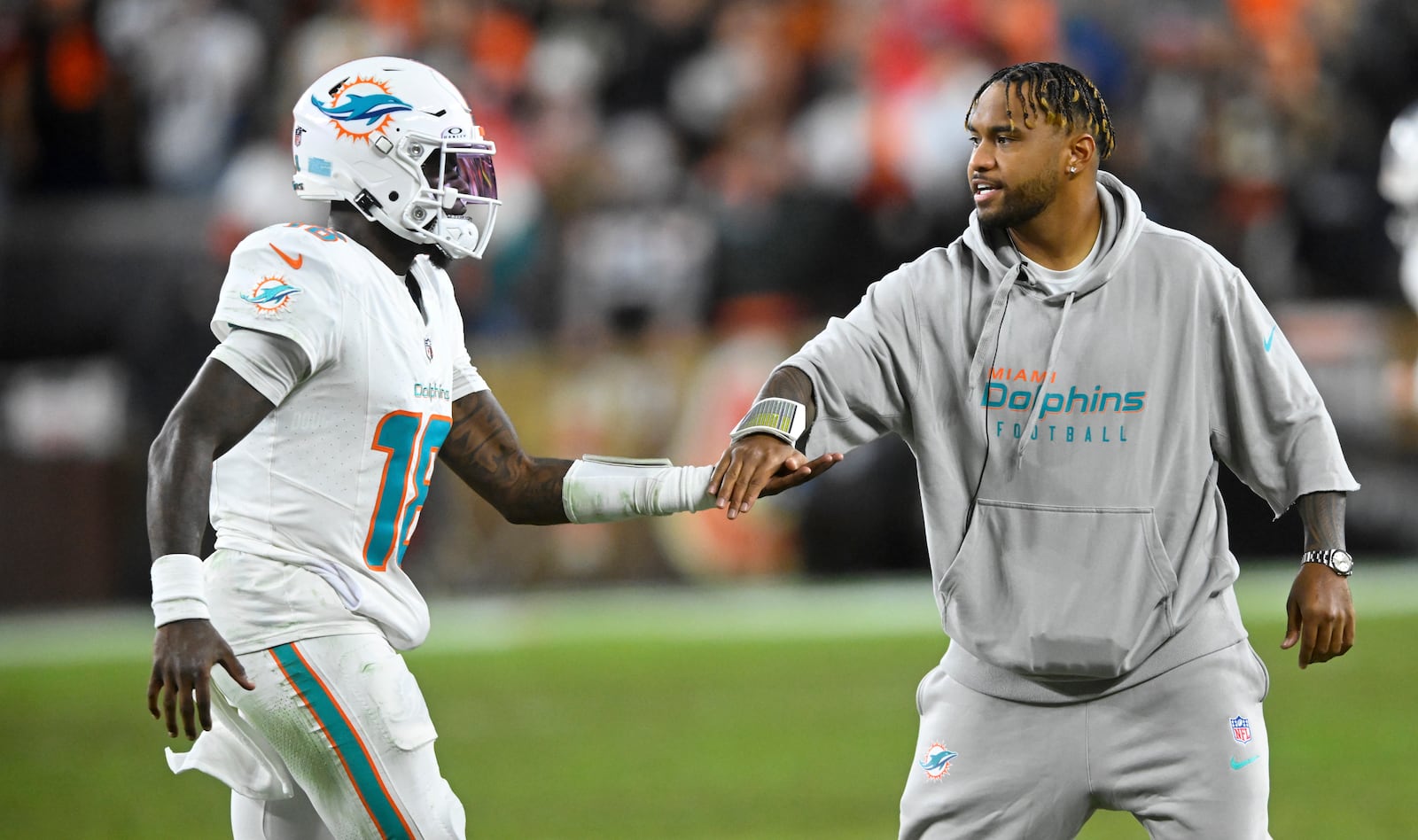 Miami Dolphins quarterback Tua Tagovailoa, right, greets quarterback Tyler Huntley (18) as he comes off the field during the first half of an NFL football game against the Cleveland Browns Sunday, Dec. 29, 2024, in Cleveland. (AP Photo/David Richard)