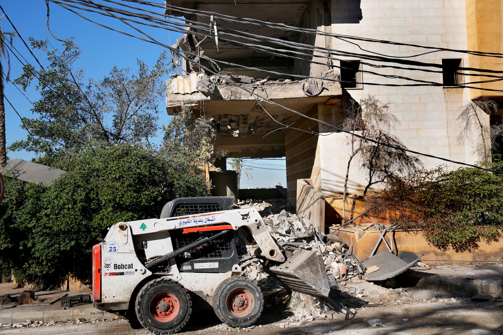 A worker uses a skid steer loader to remove the debris of a building that housed the office of pan-Arab TV channel Al-Mayadeen, which is politically allied with Hezbollah, that was hit Wednesday night by an Israeli airstrike, in southern Beirut, Lebanon, Thursday, Oct. 24, 2024. (AP Photo/Hussein Malla)