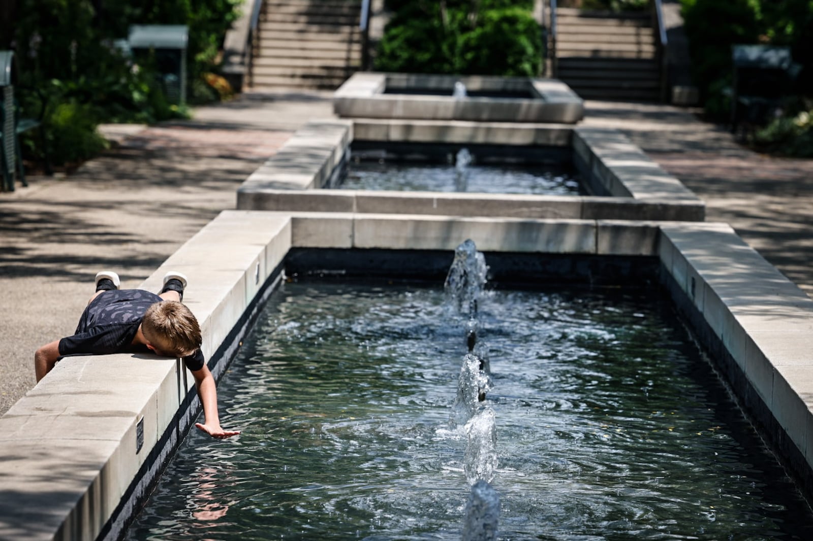 Thomas Phillips, from Dayton, enjoys the fountains at RiverScape MetroPark on Monument Ave. in downtown Dayton Wednesday July 5, 2023. JIM NOELKER/STAFF