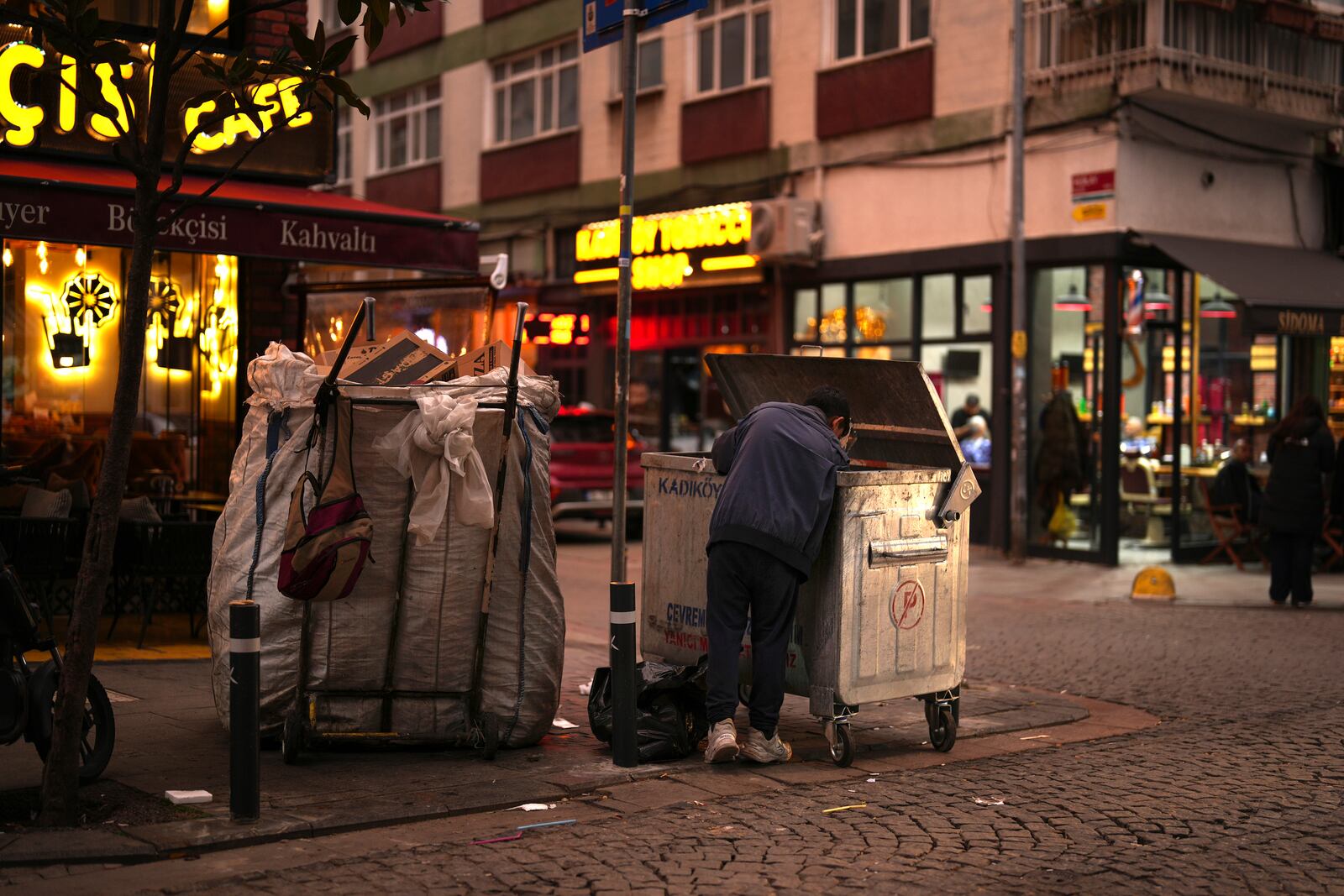 A boy scavenges for items from a trash can in the Kadikoy district in Istanbul, Turkey, Saturday, Dec. 7, 2024. (AP Photo/Francisco Seco)