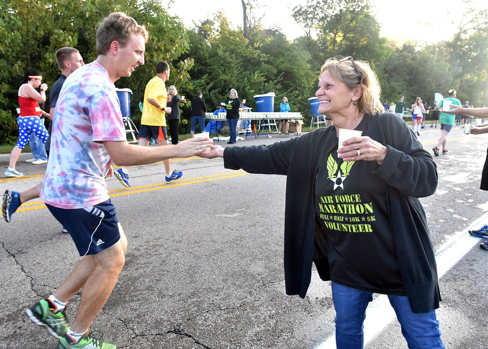 An Air Force Marathon volunteer hands out water to a runner at one of the many stations along the course Sept. 16, 2017. More than 2,400 people volunteer annually to support marathon events. (U.S. Air Force photo/Al Bright)