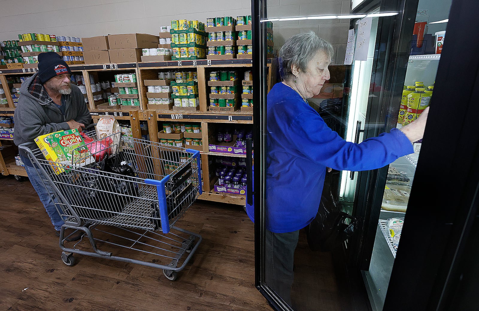 Miamisburg Helping Hands Food Pantry volunteer Carolyn Bell helps client Randy Johnson get his food on Wednesday, Feb. 12, 2025. The nonprofit organization got its start on Feb. 17, 1965. MARSHALL GORBY/STAFF