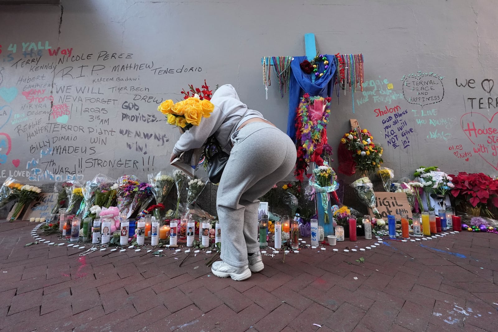 A woman places flowers at memorial on Bourbon Street for the victims of a deadly truck attack on New Year's Day in New Orleans, Friday, Jan. 3, 2025. (AP Photo/Gerald Herbert)