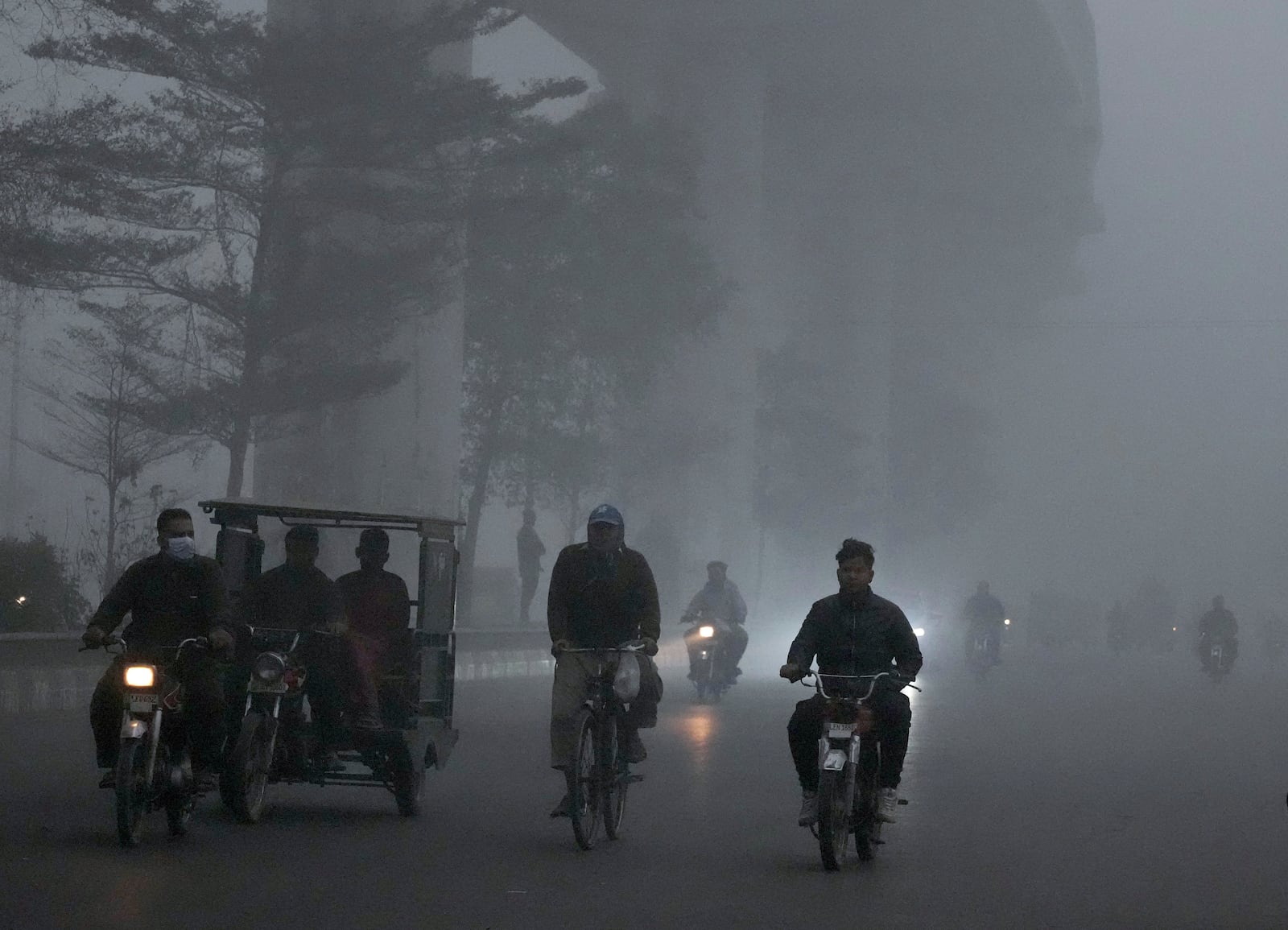 Motorcyclists move slow due to reduce visibility caused by smog enveloping the area of Lahore, Pakistan, Thursday, Nov. 14, 2024. (AP Photo/K.M. Chaudary)