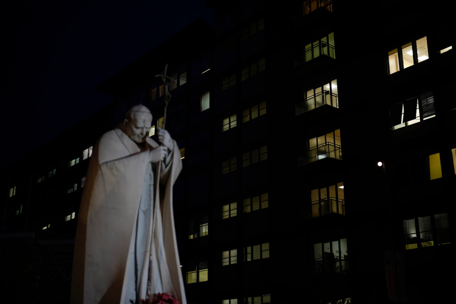 A marble statue of late Pope John Paul II is backdropped by the Agostino Gemelli Polyclinic in Rome, Monday, Feb. 17, 2025, where Pope Francis was hospitalised Friday, Feb. 14, after a weeklong bout of bronchitis worsened and is receiving drug therapy for a respiratory tract infection. (AP Photo/Gregorio Borgia)