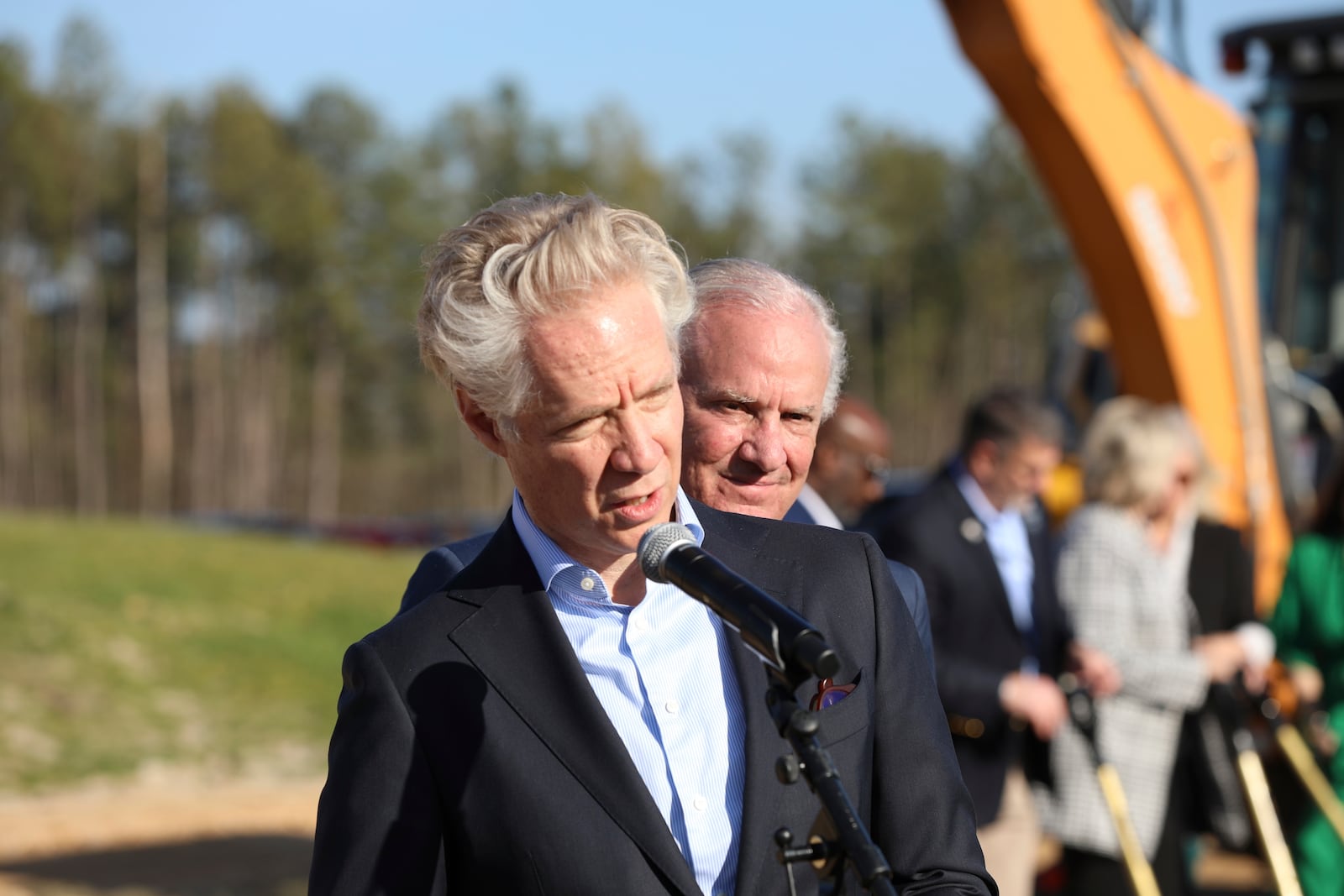 Scout Motors CEO Scott Keogh, foreground, speaks to reporters as South Carolina Republican Gov. Henry McMaster, background, listens after a groundbreaking for a new interstate exit for the Scout Motors plant on Monday, Feb. 3, 2025, in Blythewood, S.C. (AP Photo/Jeffrey Collins)