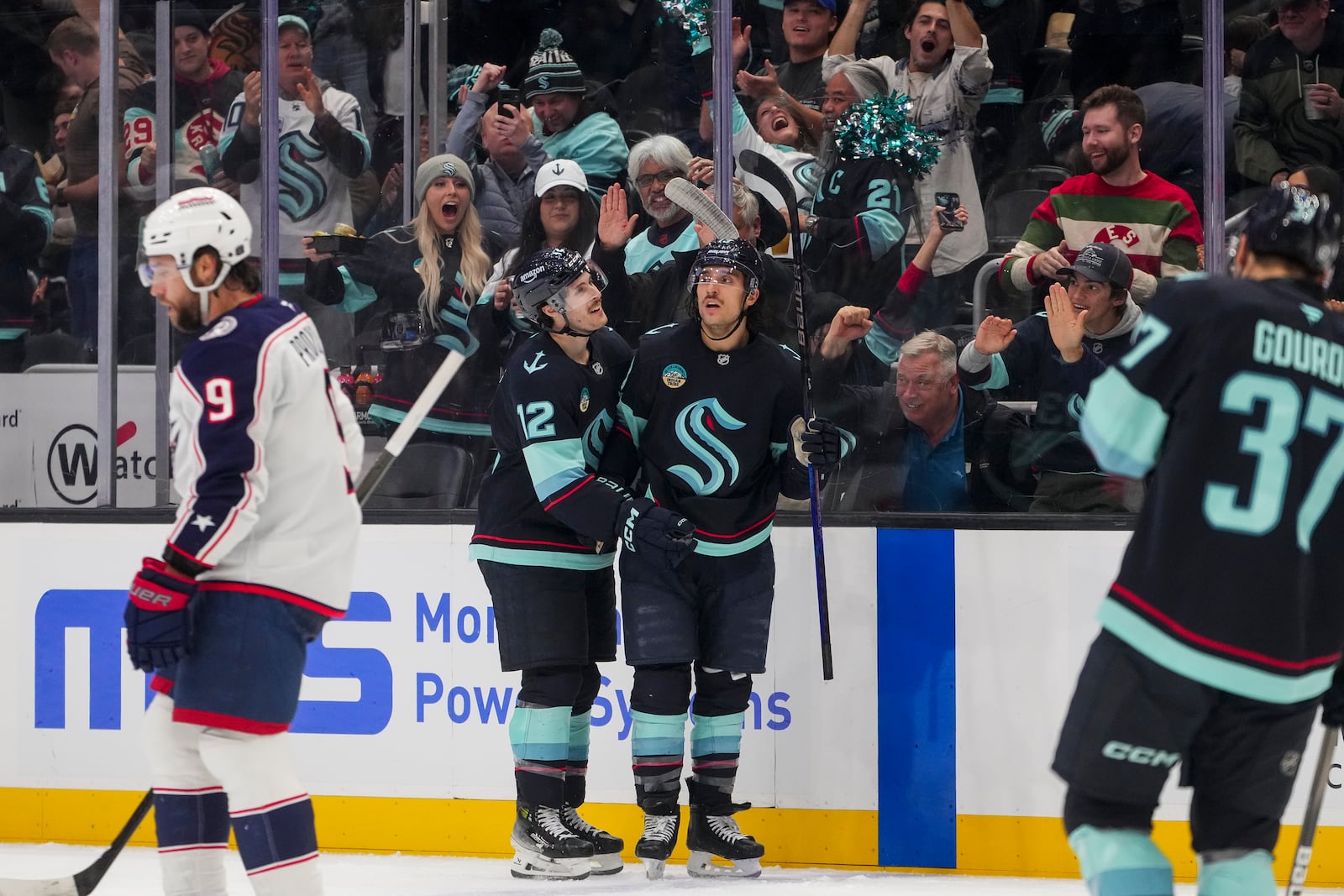 Seattle Kraken left wing Brandon Tanev, third from left, celebrates his goal with left wing Tye Kartye (12) as Columbus Blue Jackets defenseman Ivan Provorov (9) skates away during the second period of an NHL hockey game Tuesday, Nov. 12, 2024, in Seattle. (AP Photo/Lindsey Wasson)