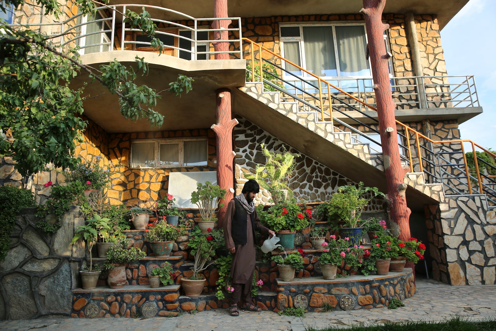 A man waters flowers outside a luxury house in the city of Kabul, Afghanistan, Sept. 29, 2024. (AP Photo/Siddiqullah Alizai)