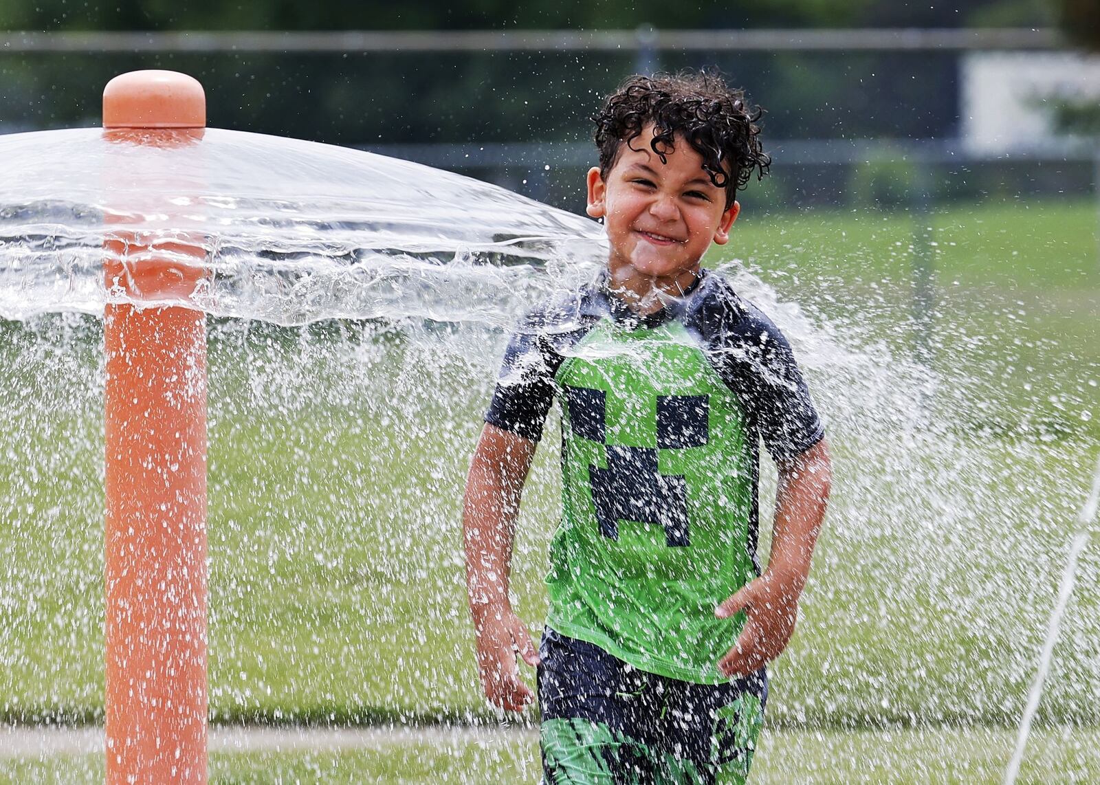 Ian Bailey, 4, cools off in the water at the spray ground at Booker T. Washington Community Center Monday, June 13, 2022 in Hamilton. NICK GRAHAM/STAFF