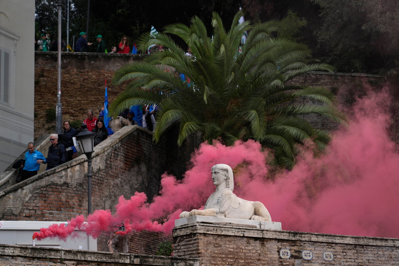 Workers of automotive sector burn flares as they arrive in Rome's Piazza Del Popolo Square during a demonstration on the occasion of their national strike, Friday, Oct. 18, 2024. (AP Photo/Gregorio Borgia)