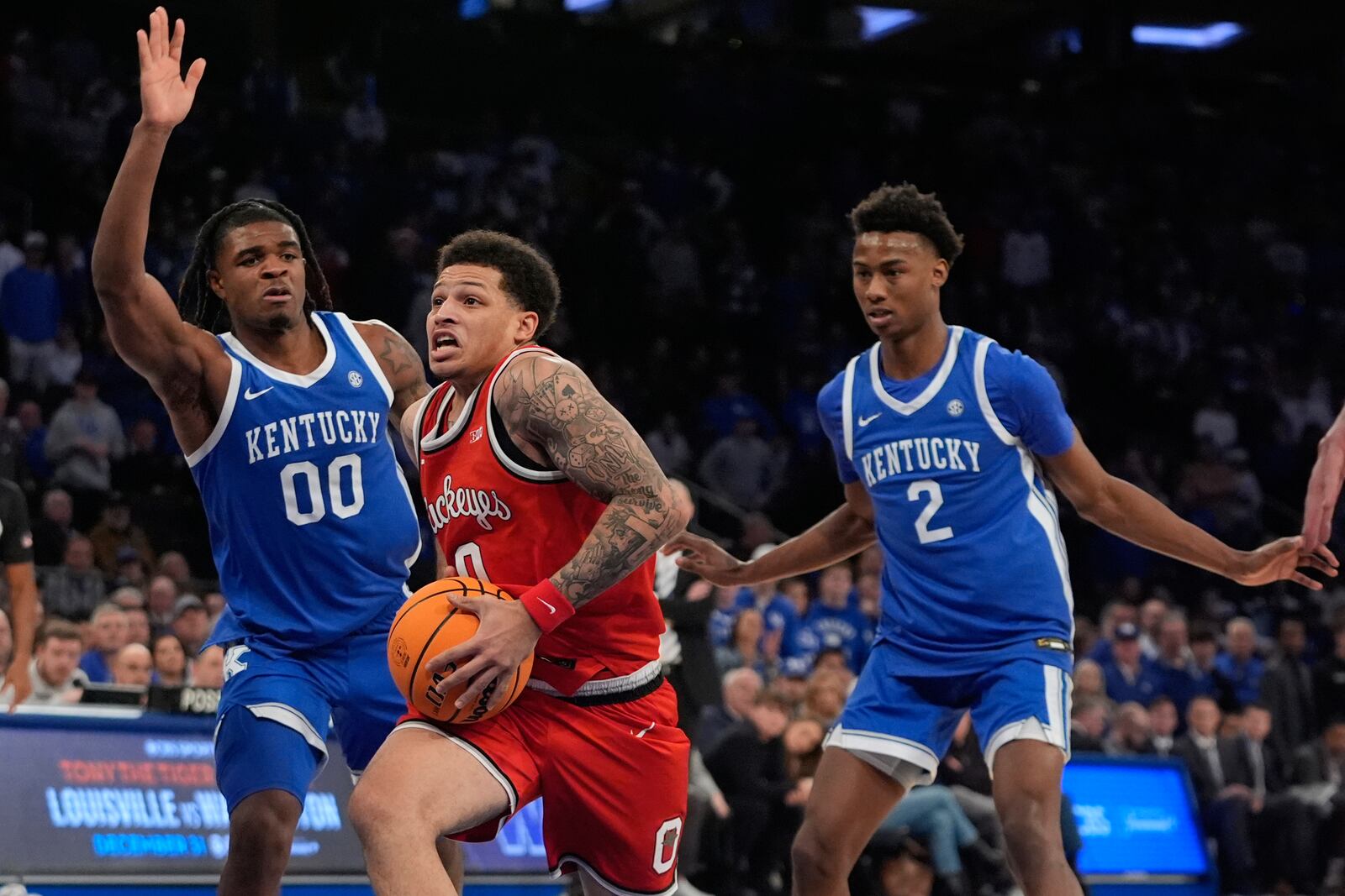 Ohio State's John Mobley Jr. (0) drives past Kentucky's Jaxson Robinson (2) and Otega Oweh (00) during the second half of an NCAA college basketball game in the CBS Sports Classic, Saturday, Dec. 21, 2024, in New York. (AP Photo/Frank Franklin II)