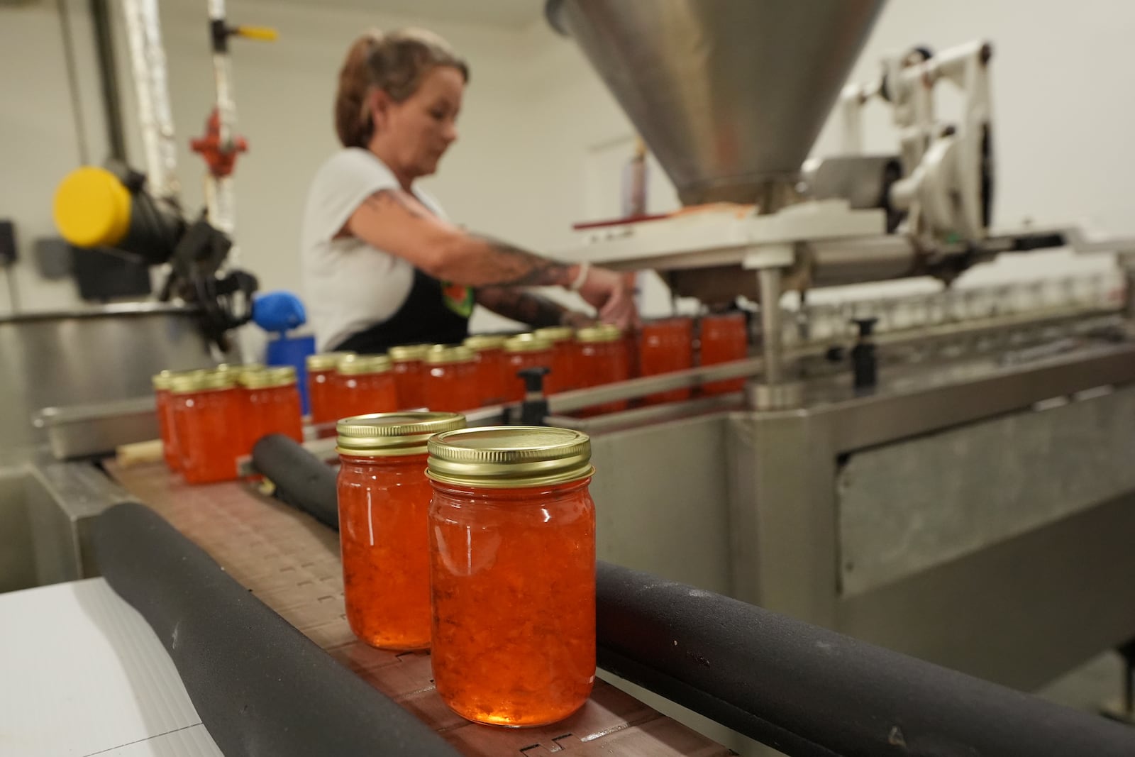 An employee at the Davidson of Dundee Citrus Candy and Jelly Factory, seals tangerine jelly containers, Tuesday, Feb. 18, 2025, in Lake Wales, Fla. (AP Photo/Marta Lavandier)