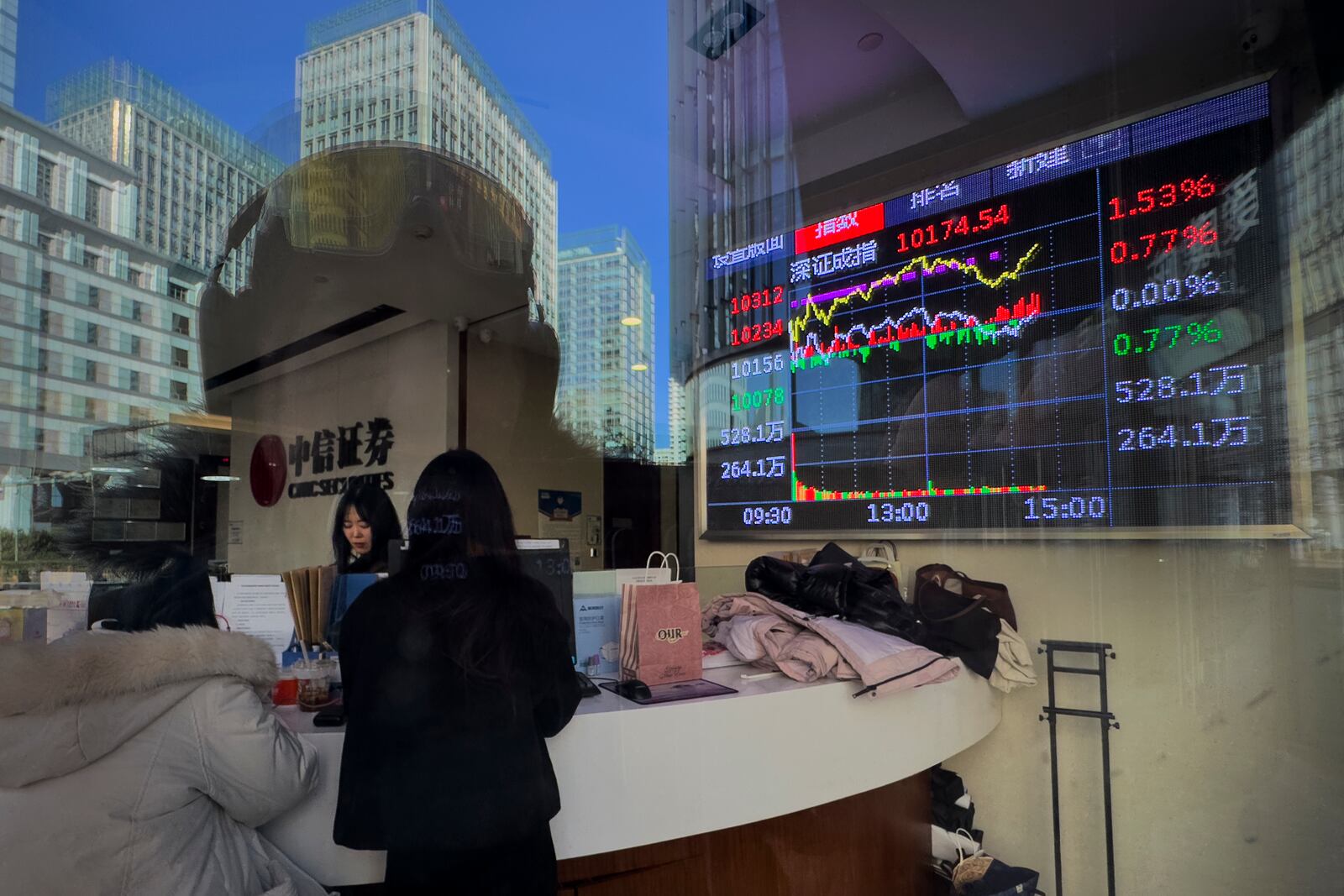 FILE - Women stand near an electronic board displaying Shenzhen shares trading index at a brokerage house in Beijing, Wednesday, Feb. 5, 2025. (AP Photo/Andy Wong, File)