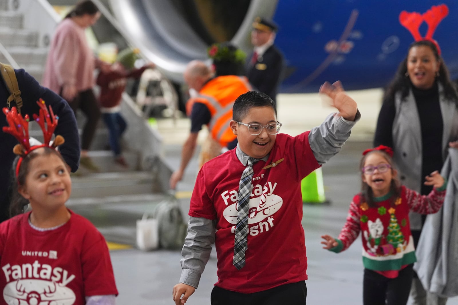 Twelve-year-old Adan Cervantes, center, of Denver, waves as he disembarks from a plane during the United Airlines annual "fantasy flight" to a fictional North Pole at Denver International Airport, Saturday, Dec. 14, 2024, in Denver. (AP Photo/David Zalubowski)