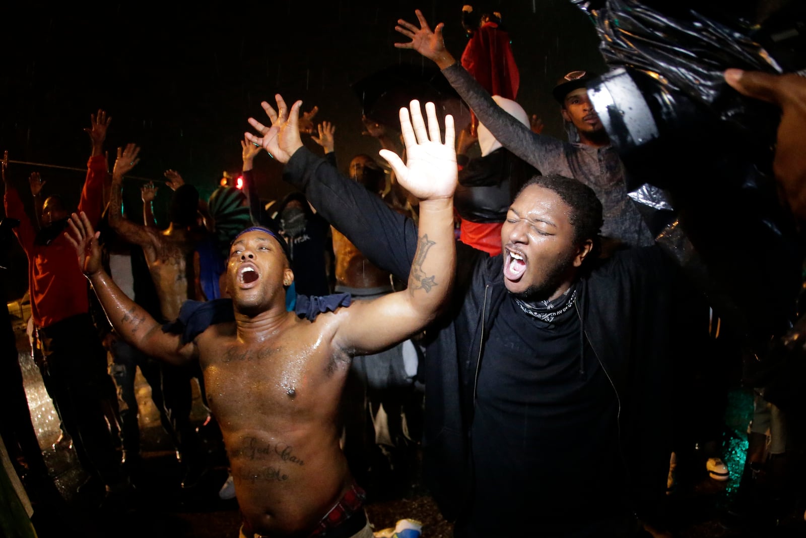 FILE - People defy a curfew on Aug. 17, 2014, before tear gas was fired to disperse a crowd protesting the shooting of teenager Michael Brown in Ferguson, Mo. (AP Photo/Charlie Riedel, File)