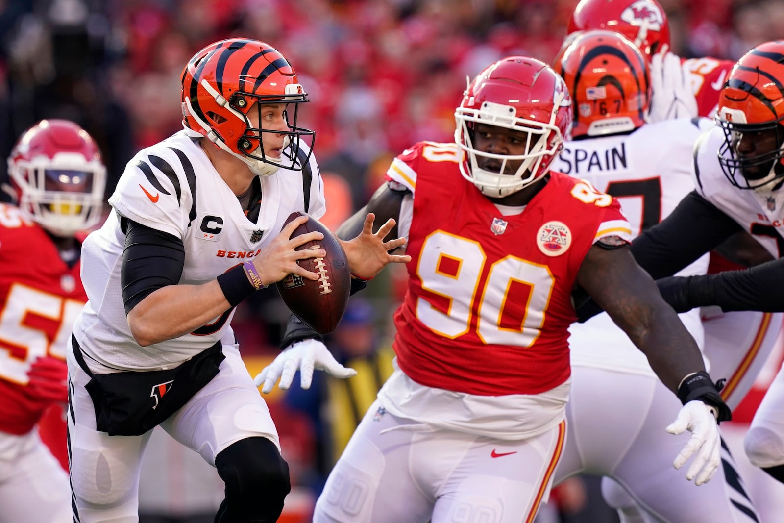 Cincinnati Bengals quarterback Joe Burrow (9) scrambles out of the pocket under pressure from Kansas City Chiefs defensive tackle Jarran Reed (90) during the first half of the AFC championship NFL football game, Sunday, Jan. 30, 2022, in Kansas City, Mo. (AP Photo/Eric Gay)