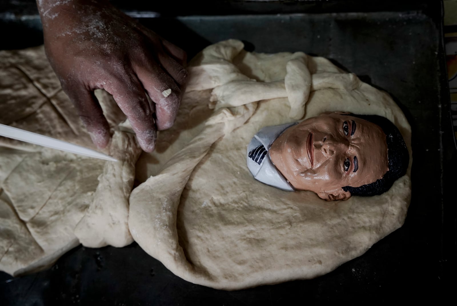 Artisan William Luna places a plaster mask at a tantawawa bread for the Mendoza family as Bolivia celebrates the Day of the Dead bread adorned with masks of loved ones in La Paz, Bolivia, Thursday, Oct. 31, 2024. (AP Photo/Freddy Barragan)