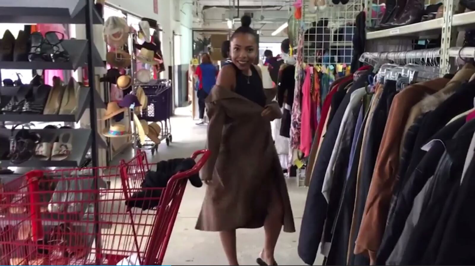 Reporter Corvaya Jeffries tries on a trench coach at the Community Thrift Shop in Riviera Beach. 