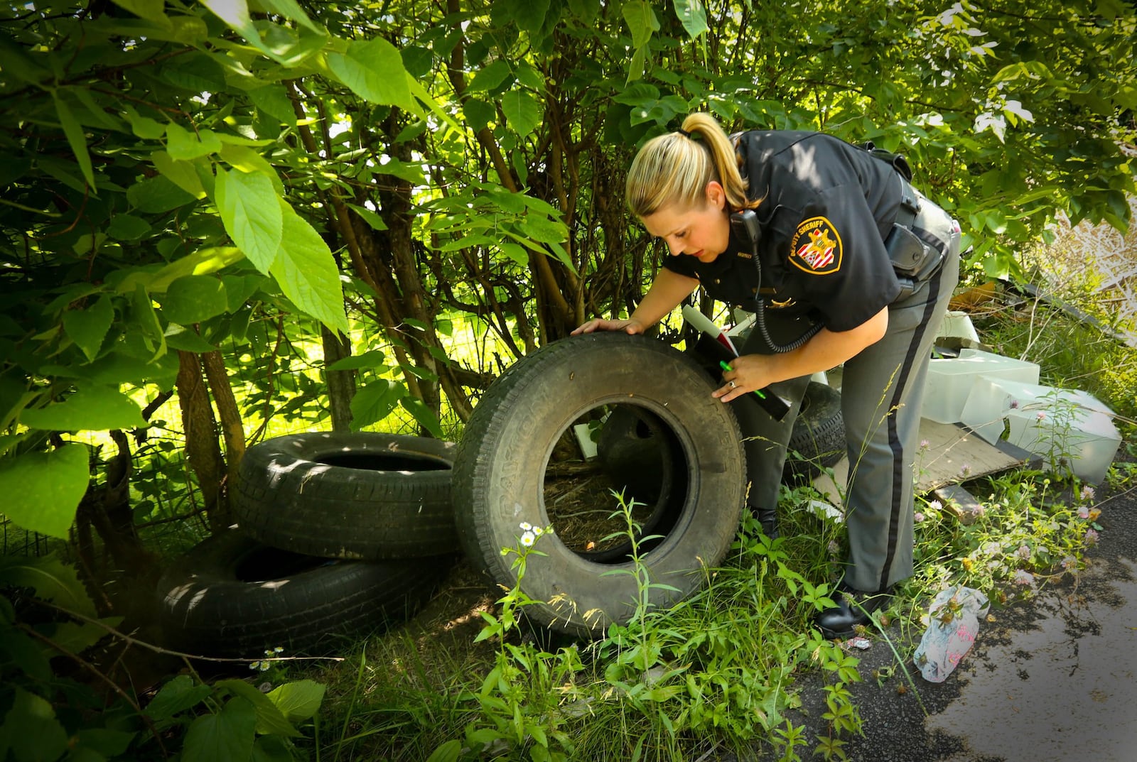 Victoria Dingee, an Environmental Enforcement officer with the Montgomery County Sheriff’s Office (MCSO)investigates a pile of illegally dumped tires in an alley in West Dayton. In 2.5 years since its inception, the MCSO Environmental Task Force has prosecuted nearly 100 alleged˜dirty dumpers. Two deputies build cases against people who illegally dump chemicals and other waste. In many cases, they say it would be cheaper for the dumpers to use the resources the county provides to dispose of paint, chemicals and tires. JIM WITMER/STAFF