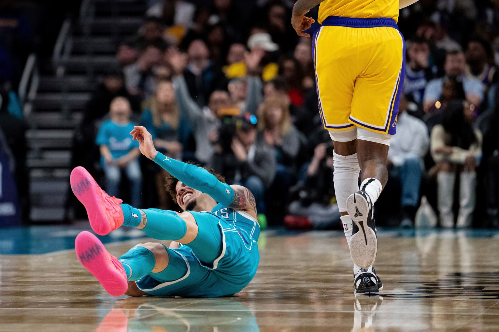 Charlotte Hornets guard LaMelo Ball, left, reacts after tripping over Los Angeles Lakers forward Jarred Vanderbilt, right, during the first half of an NBA basketball game Monday, Jan. 27, 2025, in Charlotte, N.C. (AP Photo/Jacob Kupferman)