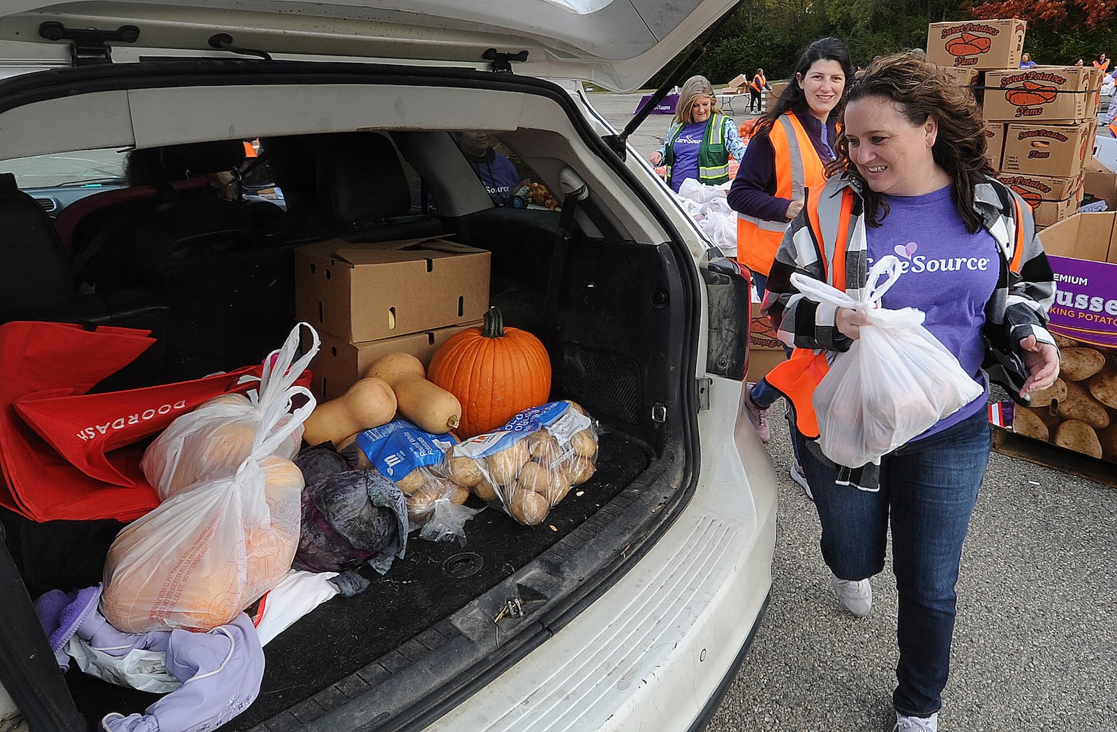 File - CareSource employees from left, Denise Johnson, Megan Post and Emily Smith place food into the back of a SUV Thursday, Oct. 19, 2023 at the mass food distribution at Wright State University’s Nutter Center. MARSHALL GORBY\STAFF