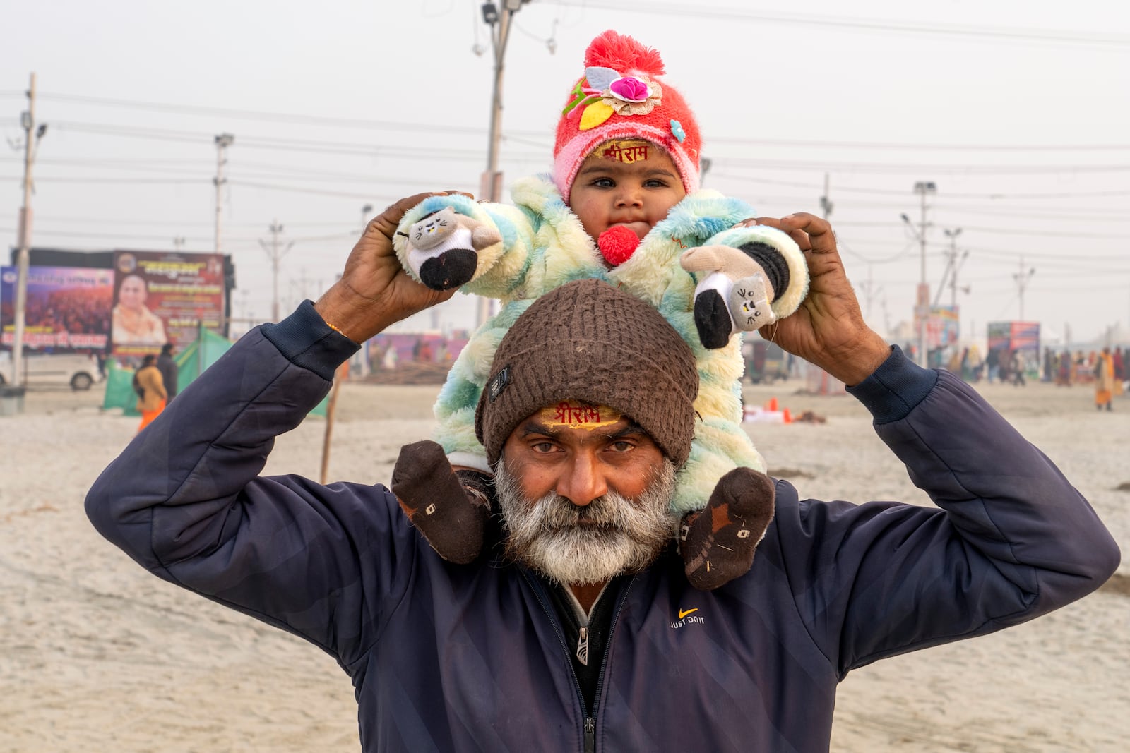 Bhagwat Prasad Tiwari and his granddaughter wear sacred marks reading 'Shree Ram' stamped in vermillion on their foreheads as they leave after bathing at the confluence of the Ganges, the Yamuna, and the Saraswati rivers the day before the 45-day-long Maha Kumbh festival in Prayagraj, India, Sunday, Jan. 12, 2025. (AP Photo/Ashwini Bhatia)