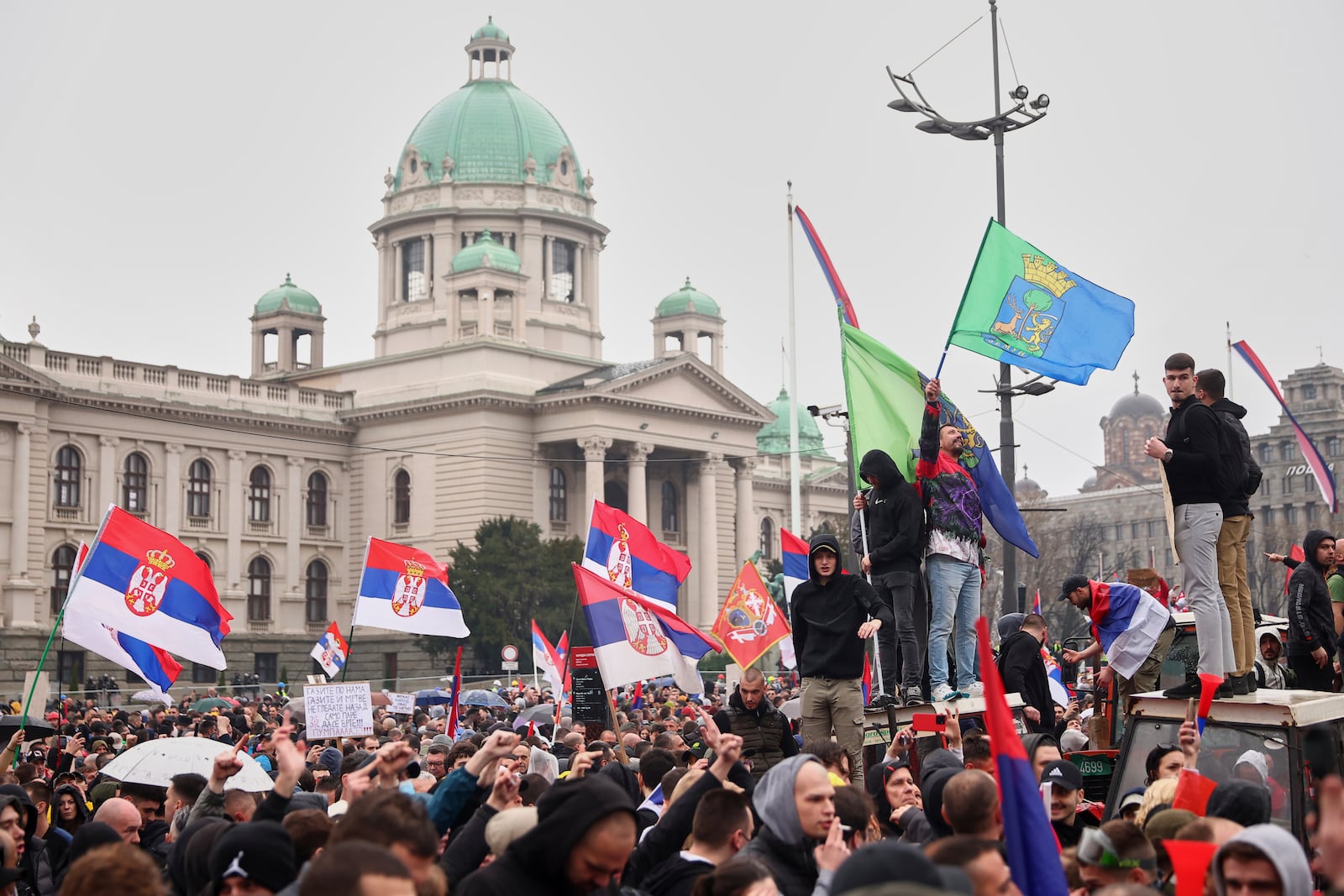 Protesters wave flags as they march past the Parliament building during a major rally against populist President Aleksandar Vucic and his government, in downtown Belgrade, Serbia, Saturday, March 15, 2025. (AP Photo/Armin Durgut)