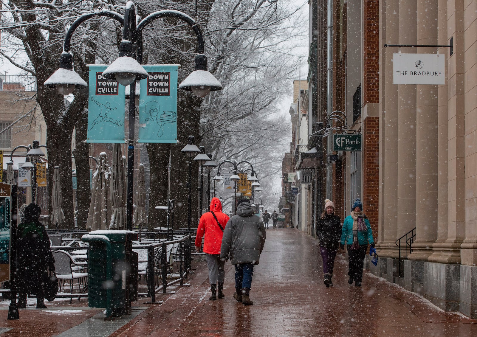 People walk along the Downtown Mall as a winter snowstorm hits Charlottesville, Va., Tuesday, Feb. 11, 2025. (Cal Cary/The Daily Progress via AP)