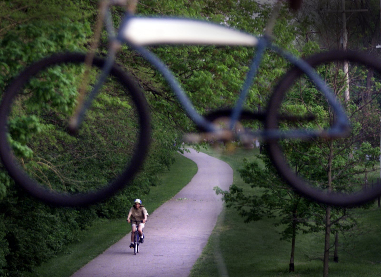 A bike hangs above the deck at the Caboose Bike and Skate shop along the bike path in Yellow Springs as a rider cruises by.