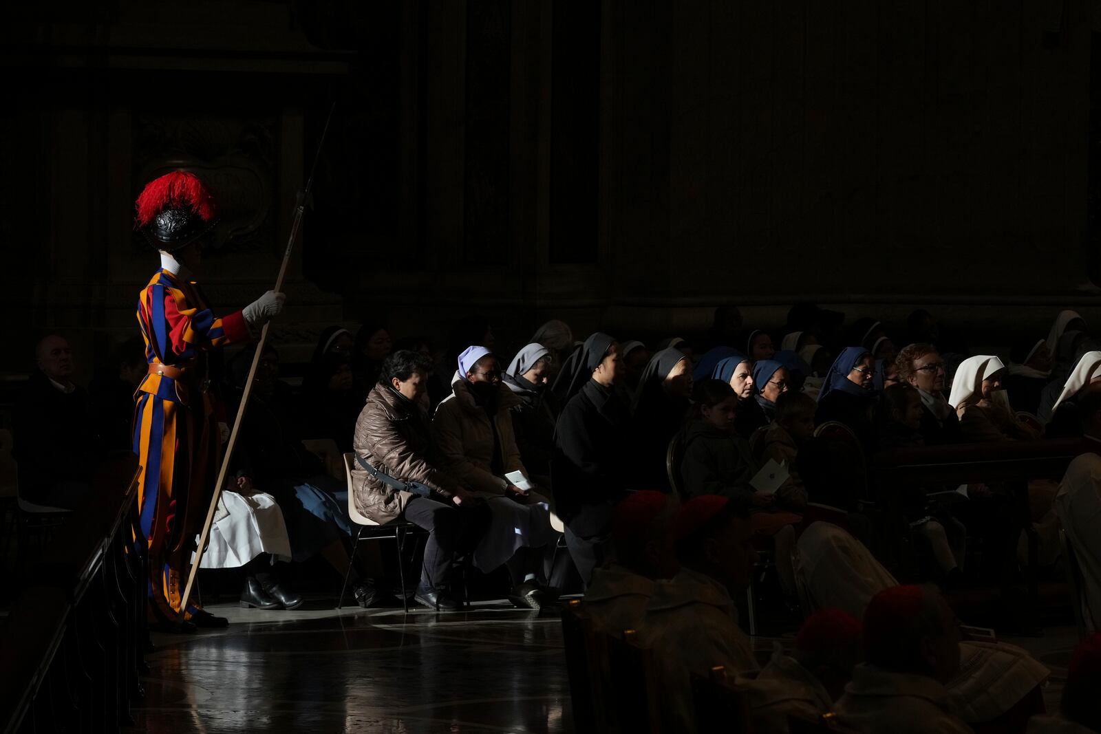 Faithful and a pontifical Swiss guard follow Pope Francis presiding over a mass in St. Peter's Basilica at The Vatican on New Year's Day, Wednesday, Jan. 1, 2025. (AP Photo/Andrew Medichini)