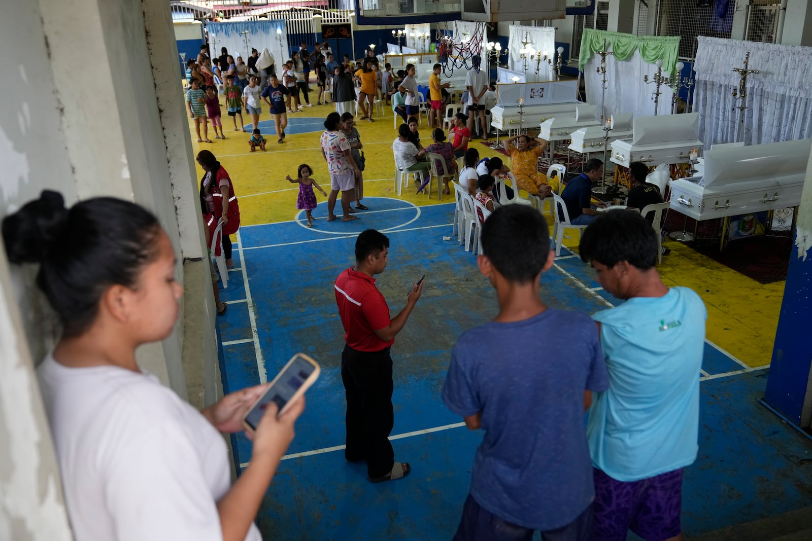 Villagers gather to pay respect to family and friends who died after a landslide hit their homes triggered by Tropical Storm Trami, in Talisay, Batangas province, Philippines, Saturday, Oct. 26, 2024. (AP Photo/Aaron Favila)