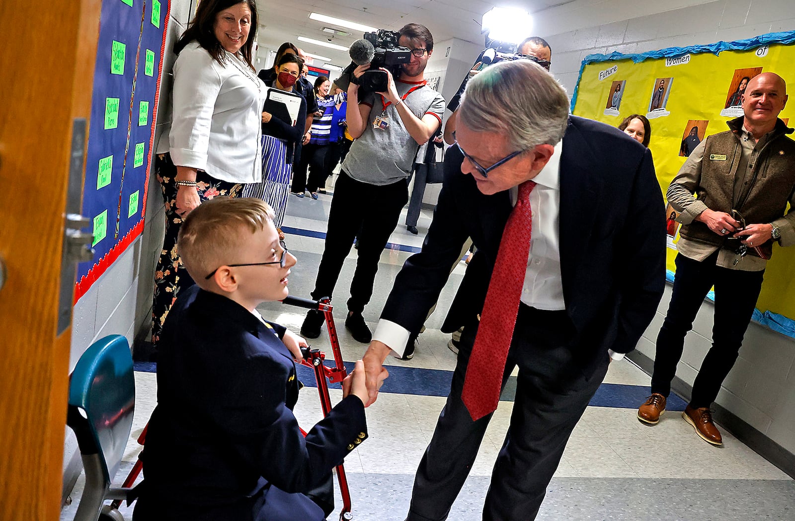 Governor Mike DeWine shakes hands with John Peale, a student ambassador at Fulton Elementary School, as he tours the Springfield City school Friday, April 14, 2023. The governor is touring schools across the state to learn about their new reading curriculum. BILL LACKEY/STAFF