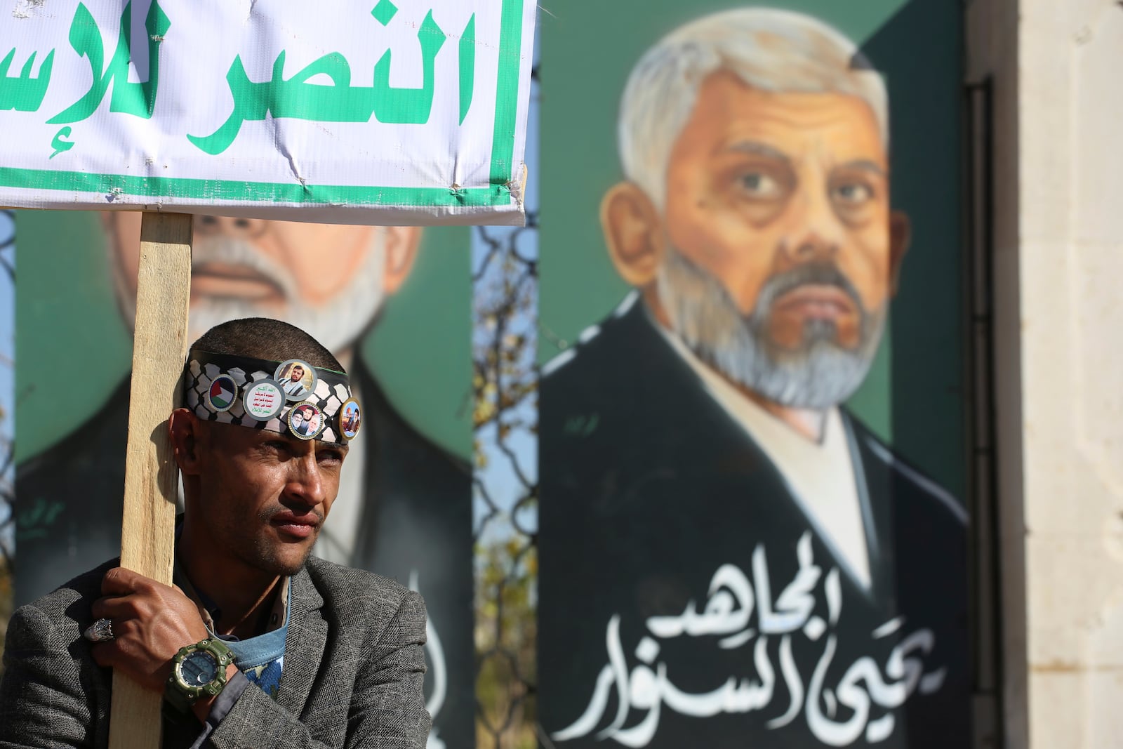 A Houthi supporter raises a banner in front of a billboard of Hamas leader Yahya Sinwar, who killed by Israeli troops in Gaza last year, during an anti-Israel rally in Sanaa, Yemen, Friday, Jan. 17, 2025. (AP Photo/Osamah Abdulrahman)