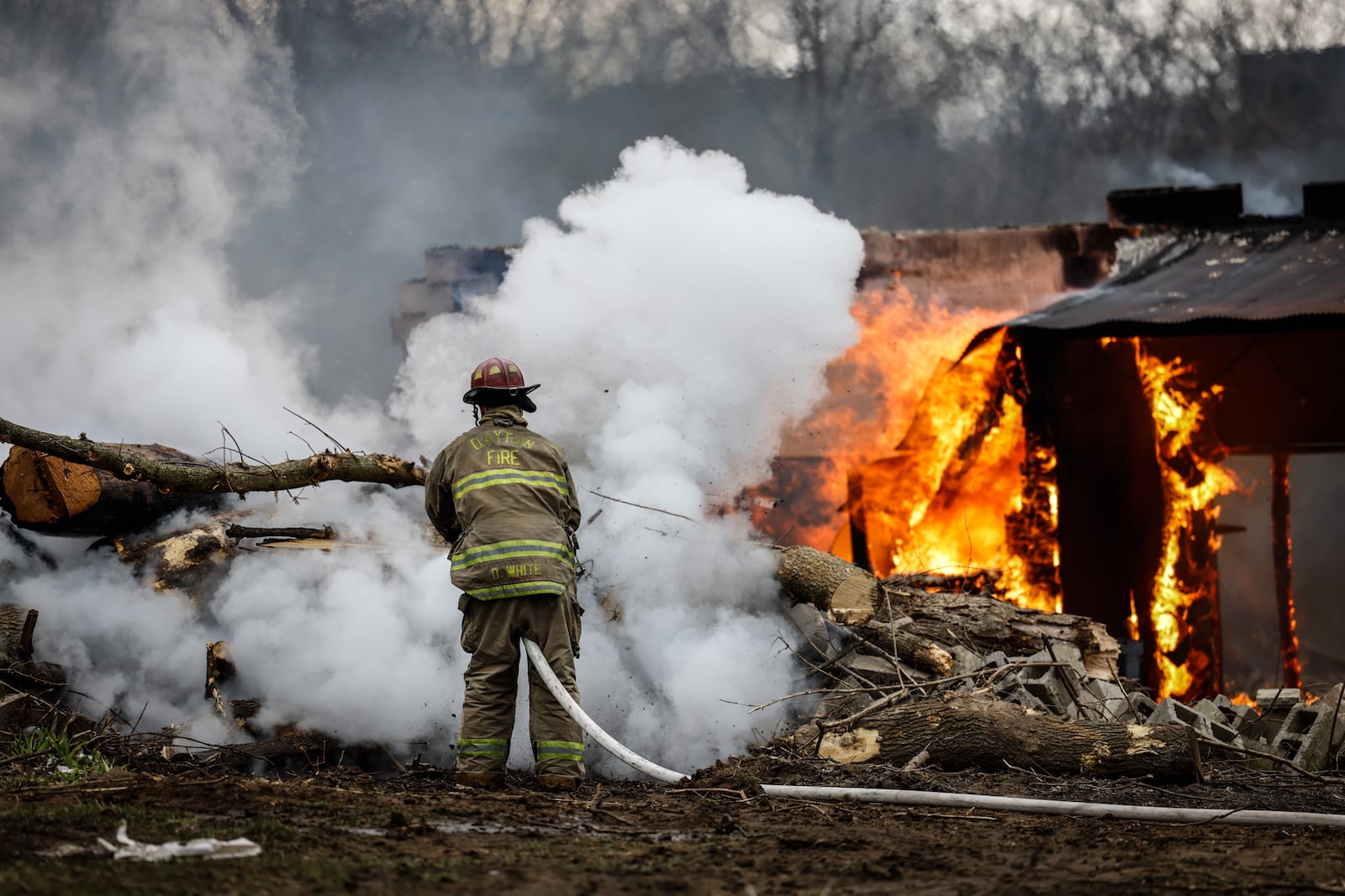 An outdoor fire apparently was spread by wind Thursday, March 31, 2022, to a wooden structure behind a house in the 3700 block of Old Troy Pike in Riverside. JIM NOELKER/STAFF