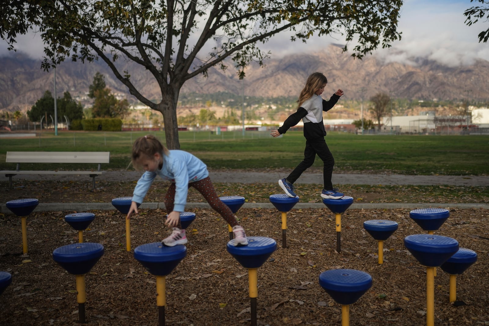 Eaton Fire evacuees Ceiba Phillips, 11, right, and his 4-year-old sister, Quoia, play at a park in Pasadena, Calif., Wednesday, Feb. 5, 2025. (AP Photo/Jae C. Hong)