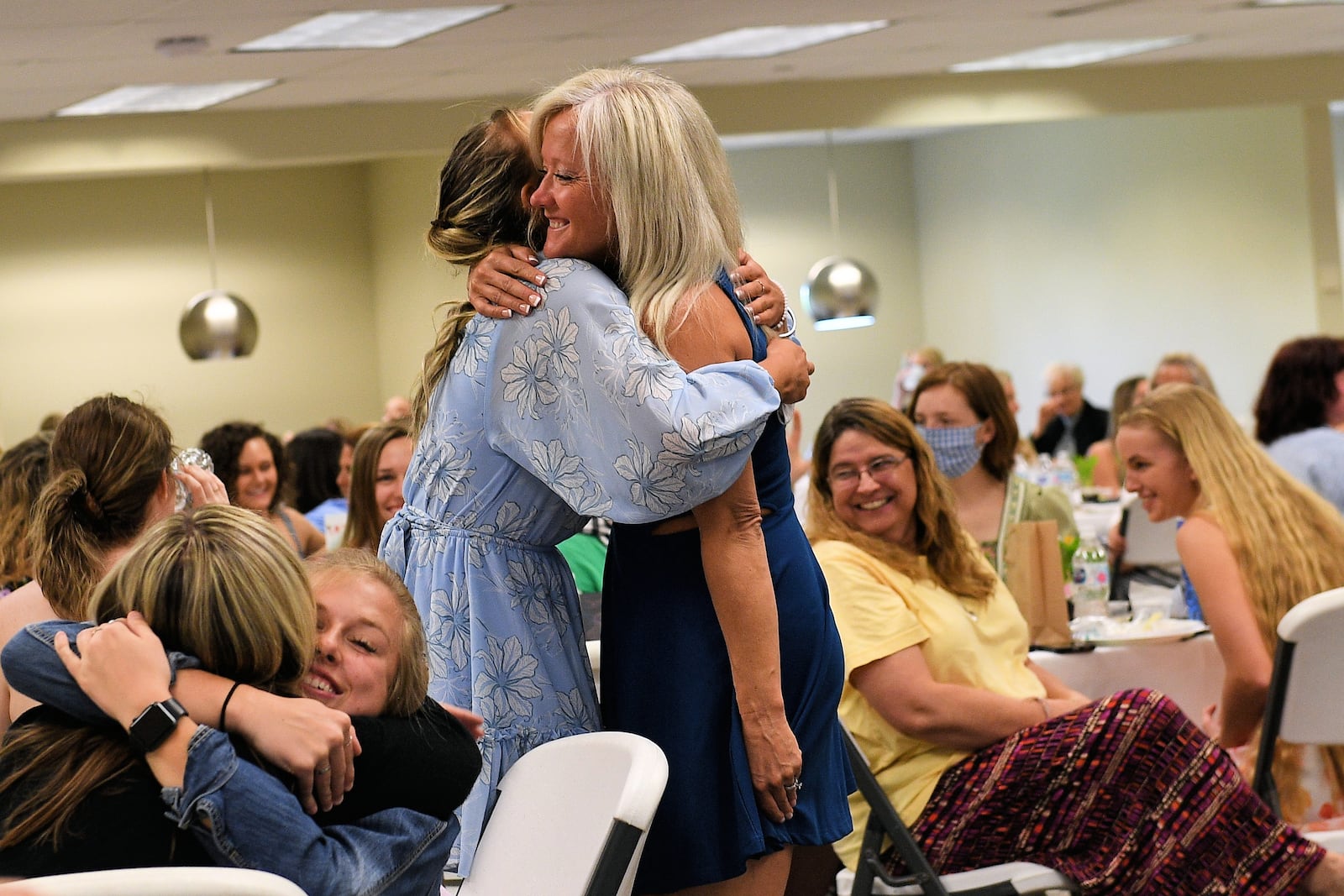 People at the 77th annual Senior Girls Tea share hugs at the urging of former superintendent Gretta Kumpf 
Kumpf during her message to the senior girls and their mothers on May 13. CONTRIBUTED