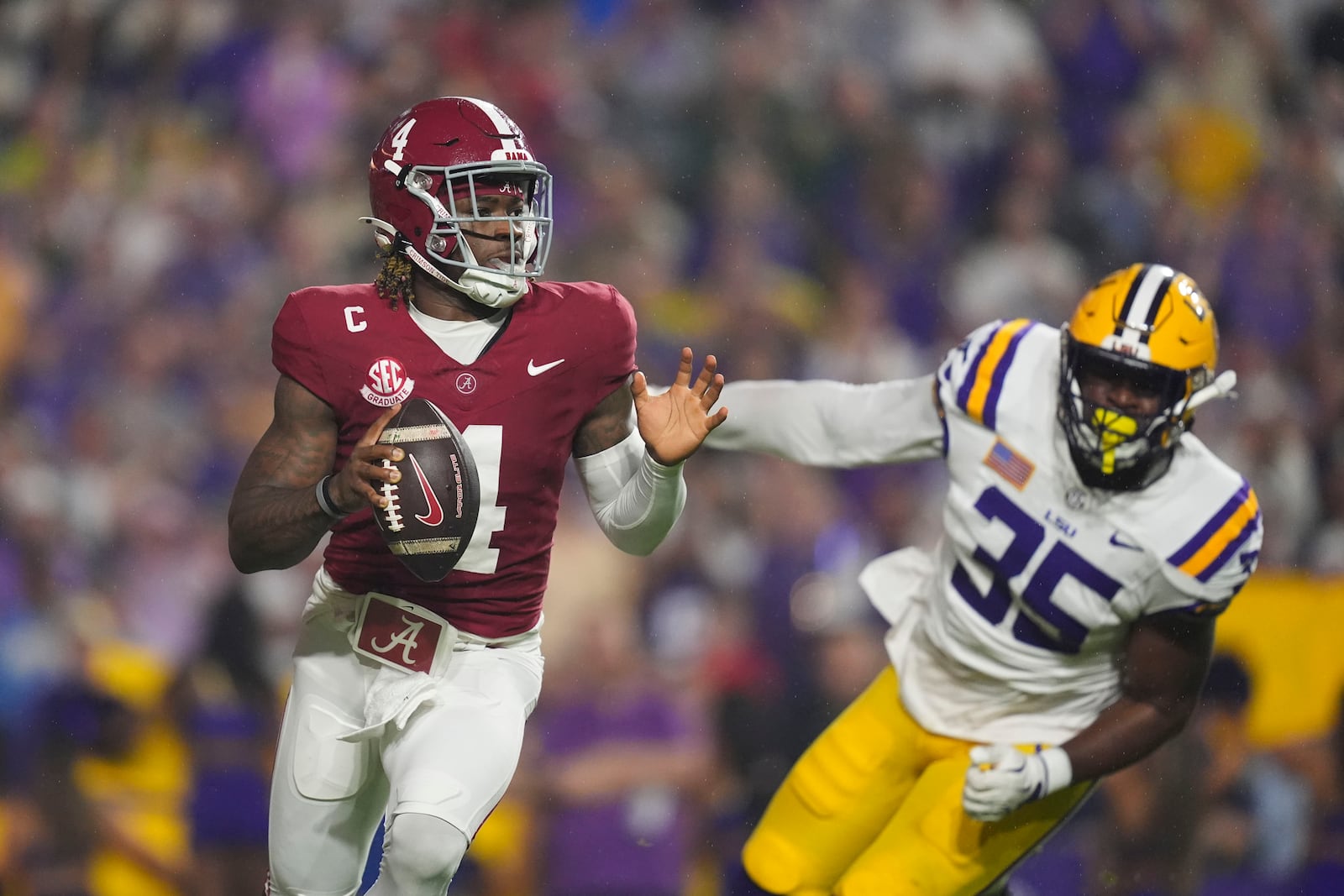 Alabama quarterback Jalen Milroe (4) rolls out under pressure from Alabama linebacker Jeremiah Alexander (35) in the first half an NCAA college football game in Baton Rouge, La., Saturday, Nov. 9, 2024. (AP Photo/Gerald Herbert)