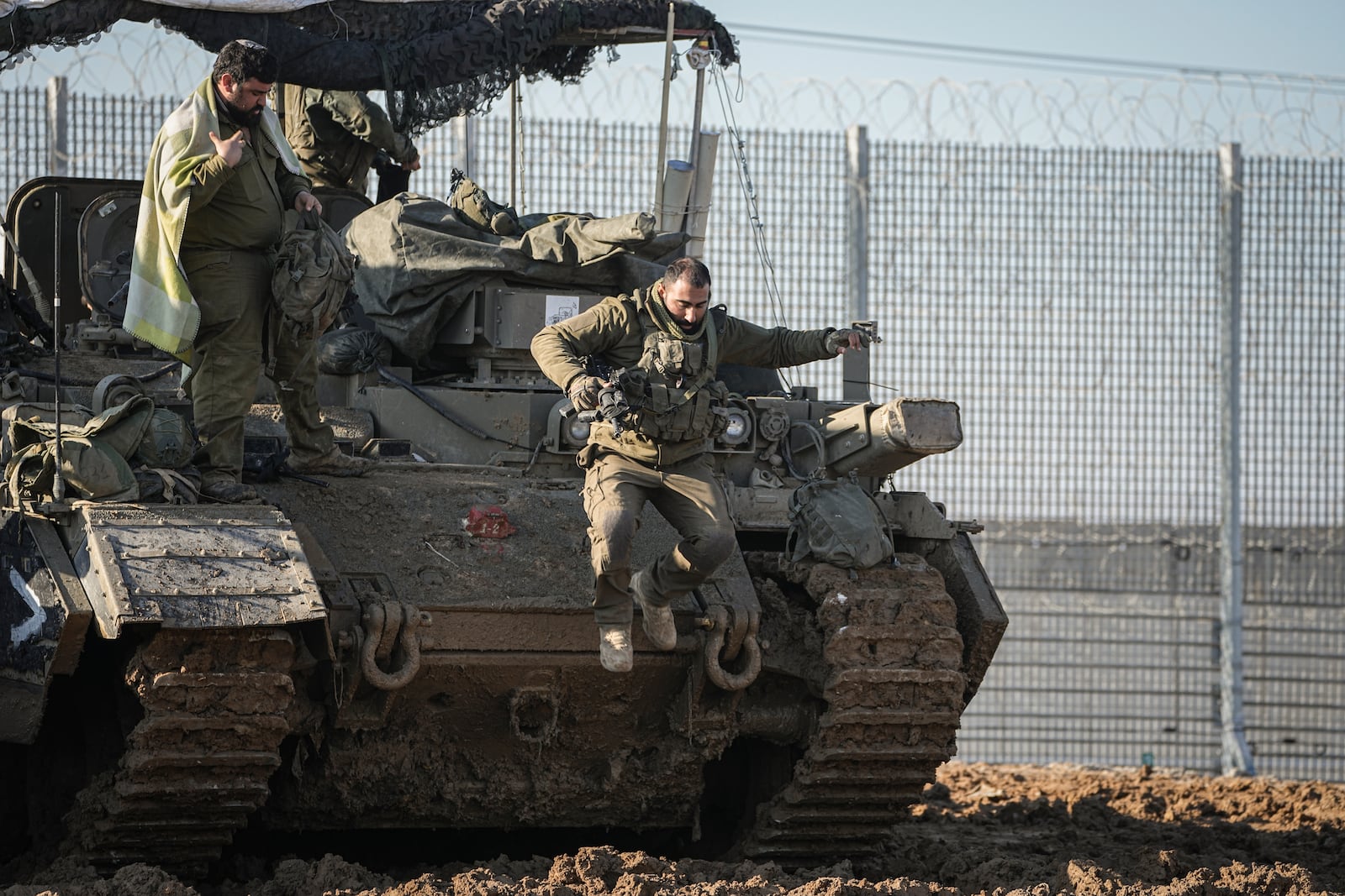 An Israeli soldier jumps off an armoured vehicle at a staging area near the Gaza border in southern Israel, Thursday Jan. 2, 2025. (AP Photo/Tsafrir Abayov))