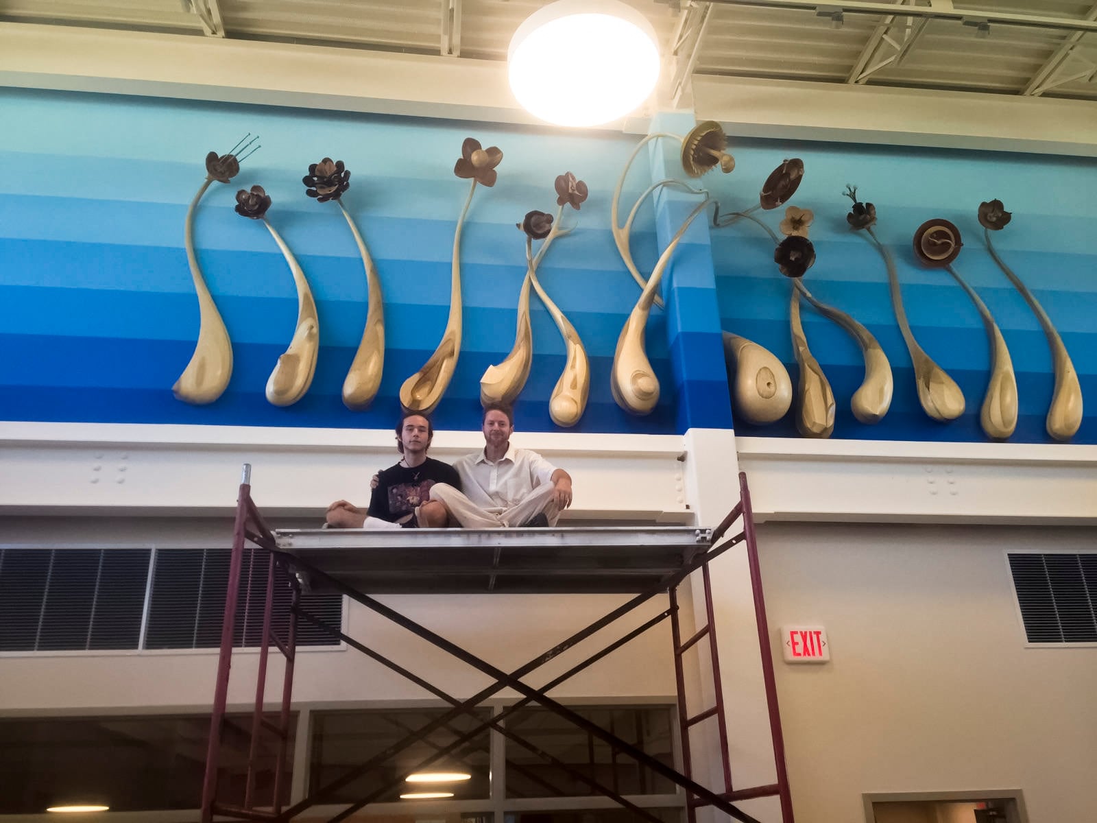 Shon Walters with son Zade, installing work titled "The Flowers' Ultimate Devouring of the Sun", at the New Lebanon Branch of the Dayton Metro Library.