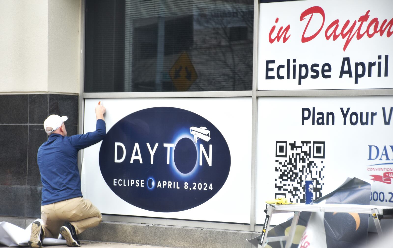 A man installs a sign on the side of the Dayton Convention Center on Feb. 21, 2024, advertising the total solar eclipse on April 8, 2024. CORNELIUS FROLIK / STAFF