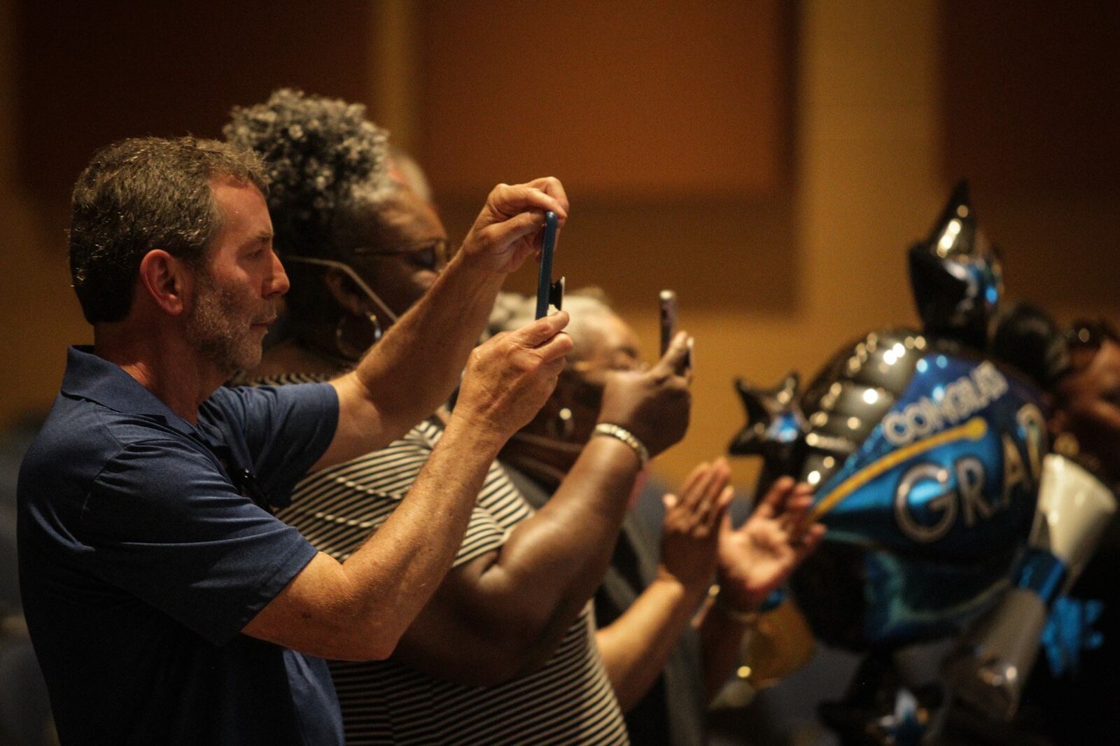 Chelsey Shellabarger’s father, Scot, left, takes pictures of his daughter graduation ceremony Friday afternoon at Brookville High School. The families home was destroyed by the 2019 Memorial Day tornado. JIM NOELKER/STAFF