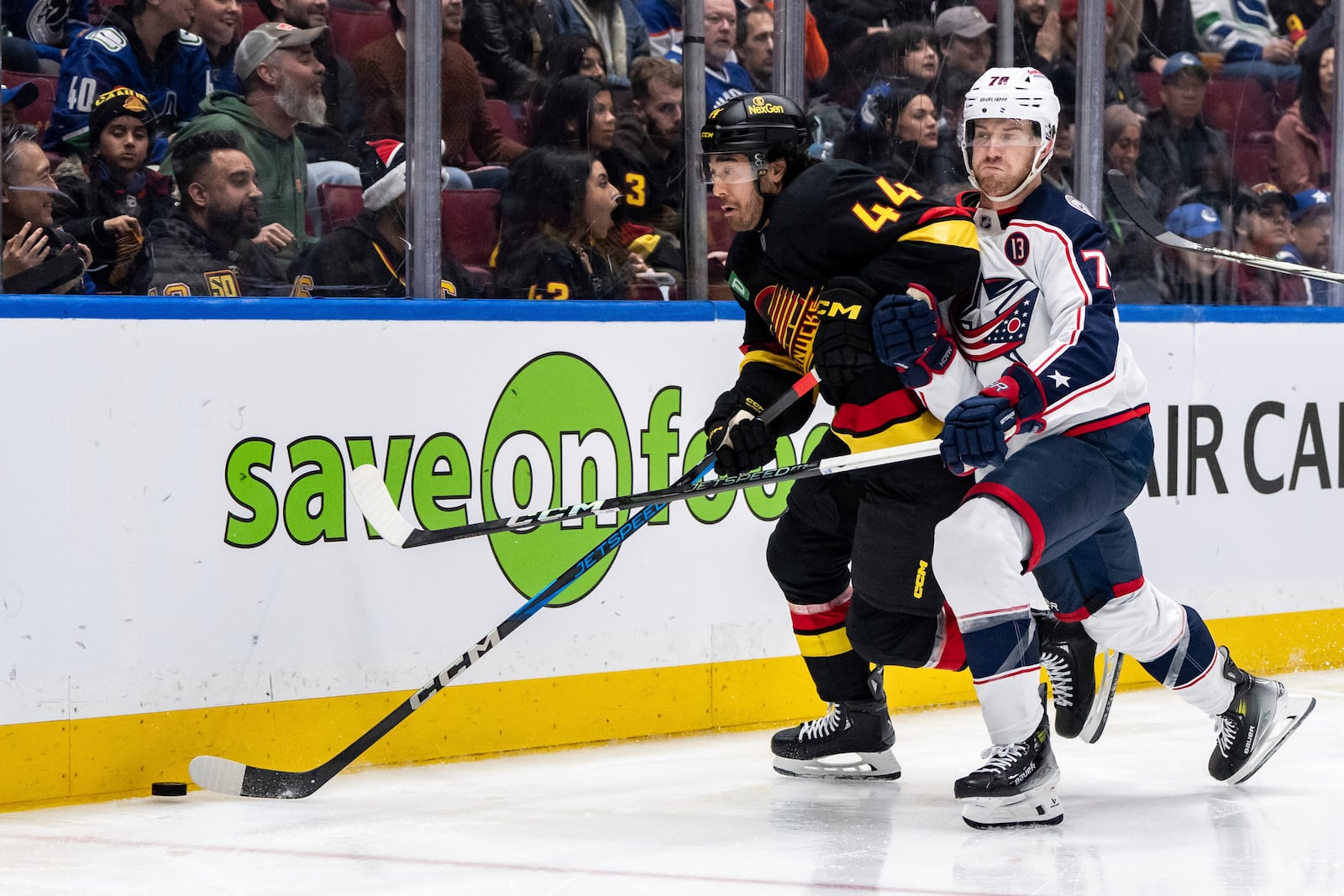 Vancouver Canucks' Kiefer Sherwood (44) and Columbus Blue Jackets' Damon Severson (78) vie for the puck during the third period of an NHL hockey game in Vancouver, British Columbia, Friday, Dec. 6, 2024. (Ethan Cairns/The Canadian Press via AP)