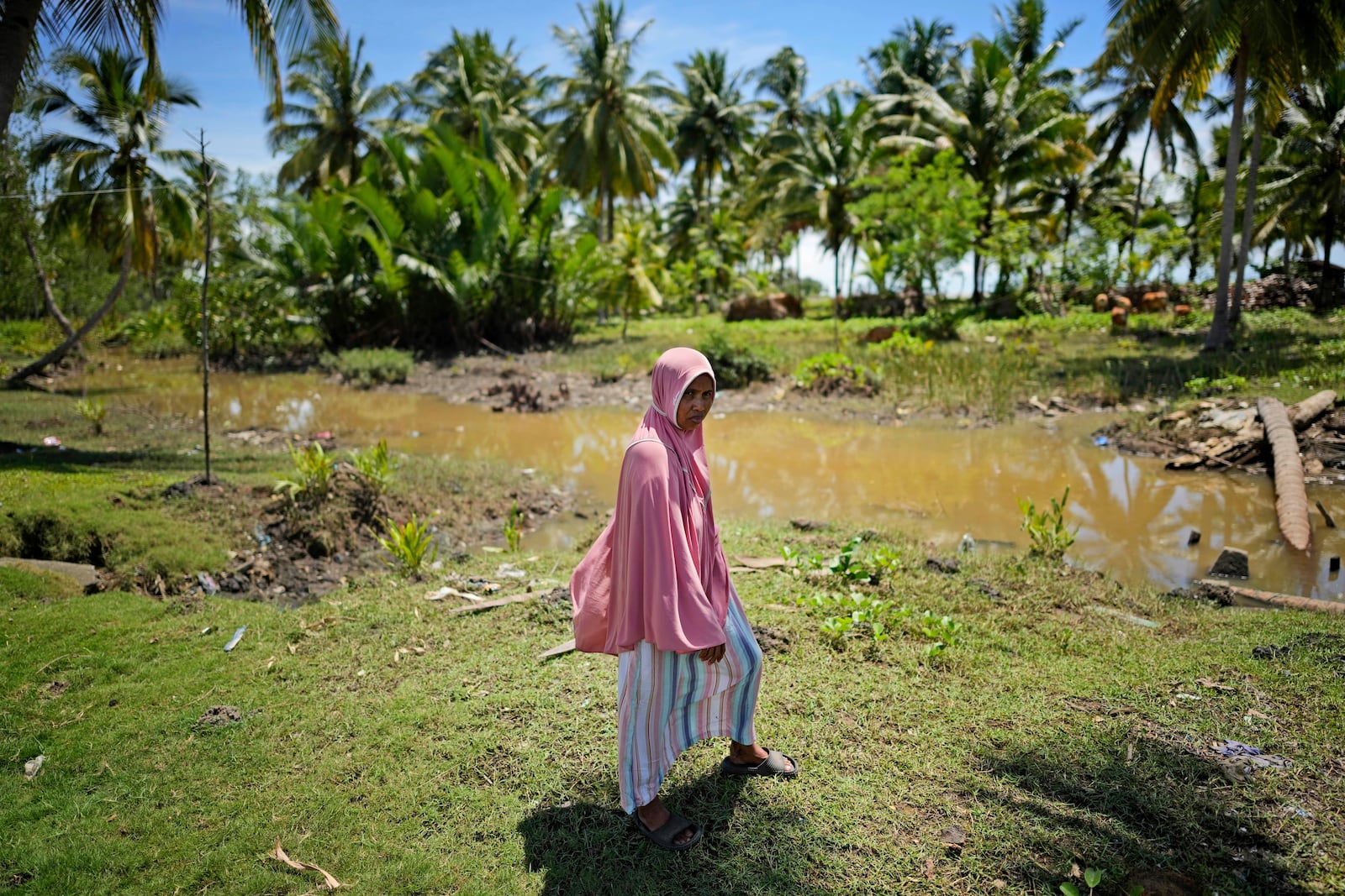 Munirpa, a crocodile attack survivor, stands for a portrait at the location where she was nearly killed by a four-meter-long crocodile, in Topoyo, West Sulawesi, Indonesia, Monday, Feb. 24, 2025. (AP Photo/Dita Alangkara)