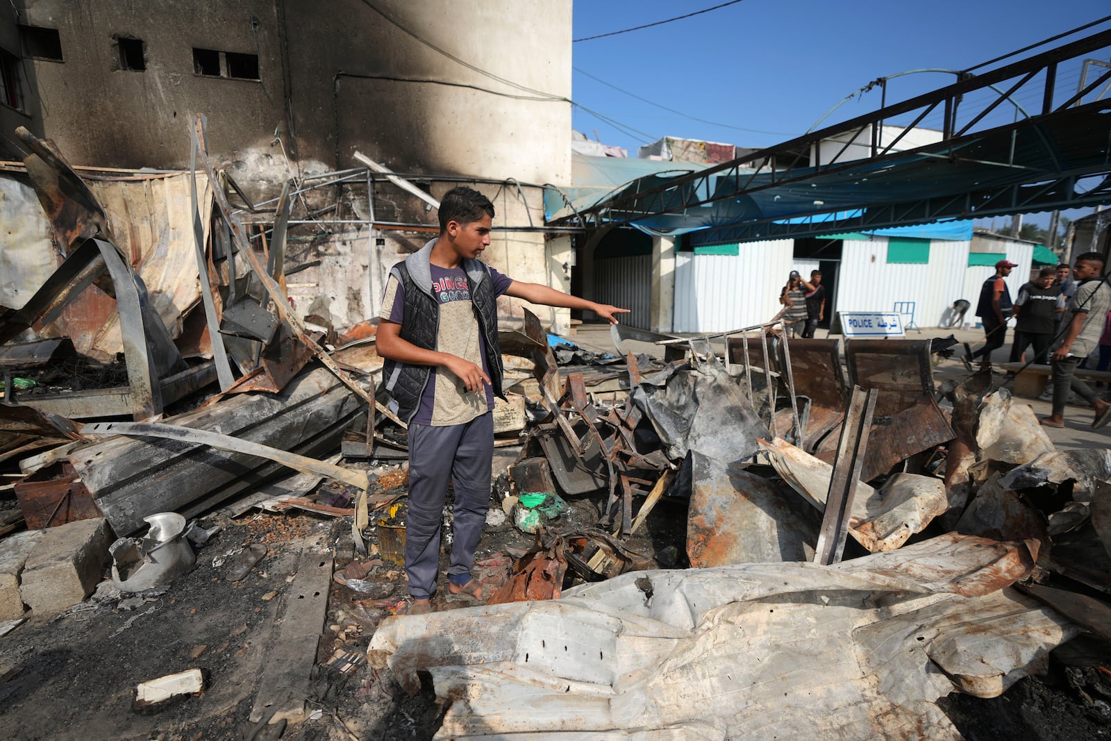 Mohamed al-Dalu gestates to the site where his brother, Shaban, was killed in a fire after an Israeli strike hit a tent area in the courtyard of Al Aqsa Martyrs hospital in Deir al-Balah, Gaza Strip, Wednesday, Oct. 16, 2024. (AP Photo/Abdel Kareem Hana)